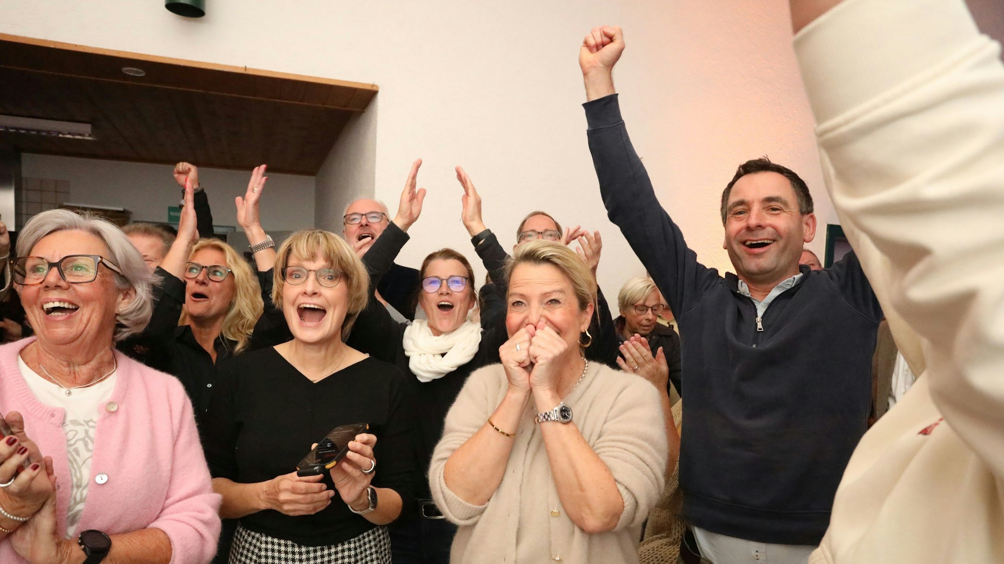 Mehrere jubeln und recken die Hände hoch.