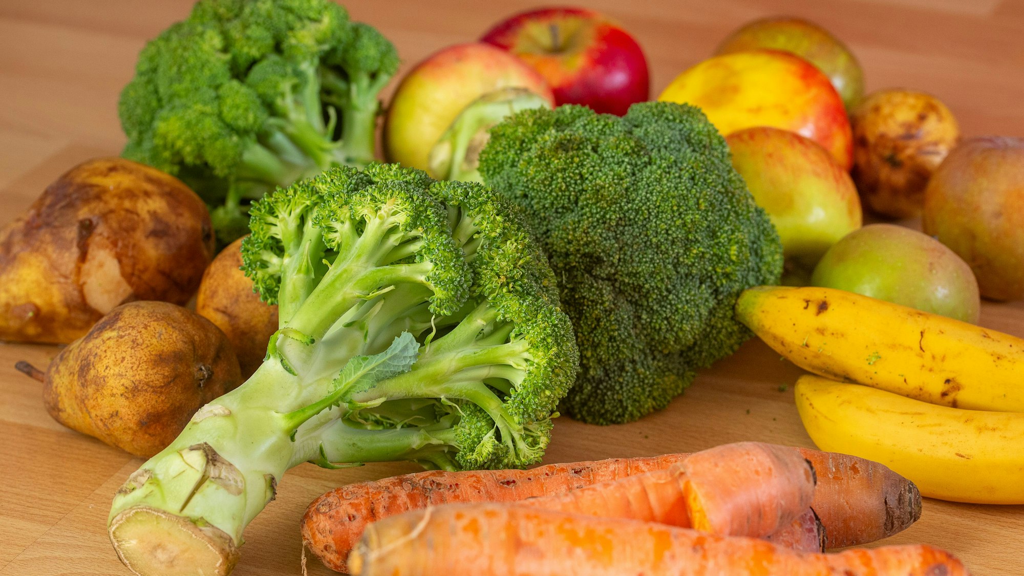 Gerettete Lebensmittel liegen auf dem Boden, darunter Brokkoli, Äpfel, Bananen, Karotten und Birnen. (Symbolbild)