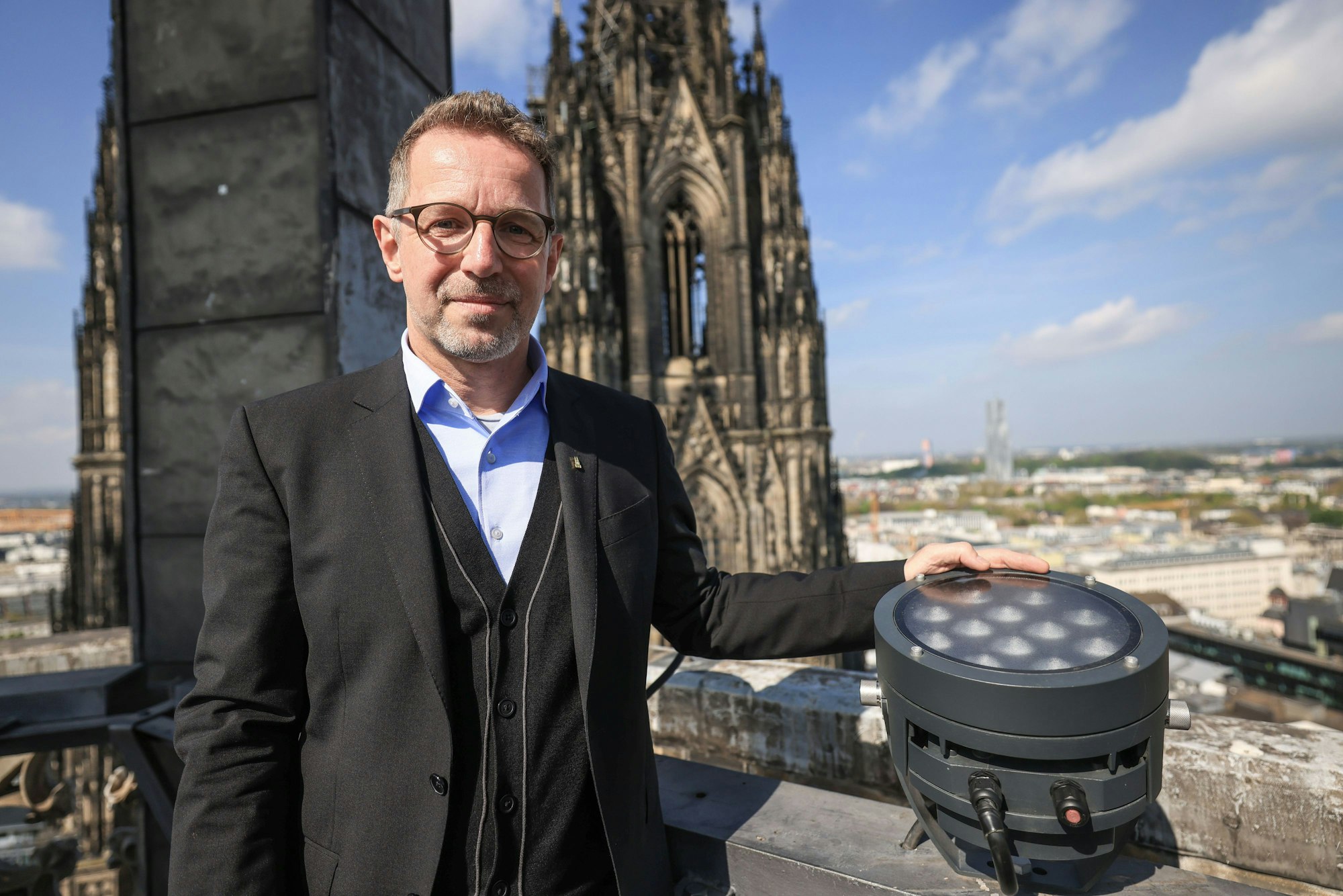 PRODUKTION - 14.04.2025, Nordrhein-Westfalen, Köln: Peter Füssenich, Dombaumeister, steht im Vierungsturm neben einer neuen LED-Lampe. Der Kölner Dom wird von Ostersonntag an komplett neu angestrahlt. (zu dpa: «Kölner Dom ab Ostern mit neuer Beleuchtung») Foto: Oliver Berg/dpa +++ dpa-Bildfunk +++