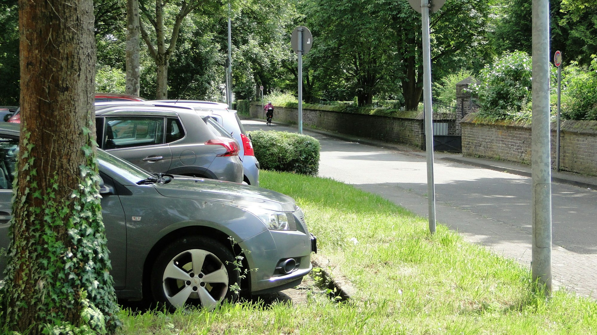 Autos parken auf einem Stellplatz am Friedhof in Weiler.