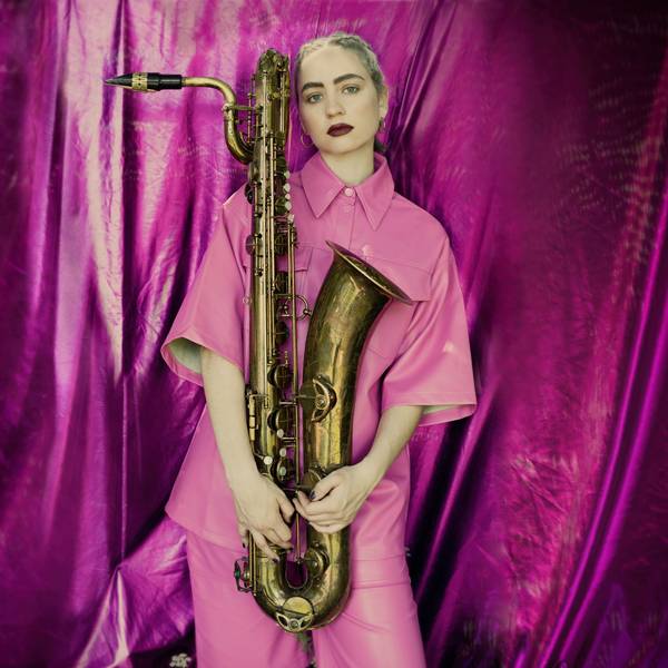 Baritonsaxofonistin Kira Linn mit ihrem Instrument in rosa Anzug