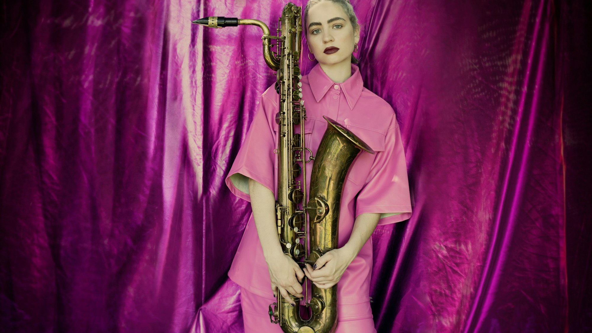 Baritonsaxofonistin Kira Linn mit ihrem Instrument in rosa Anzug