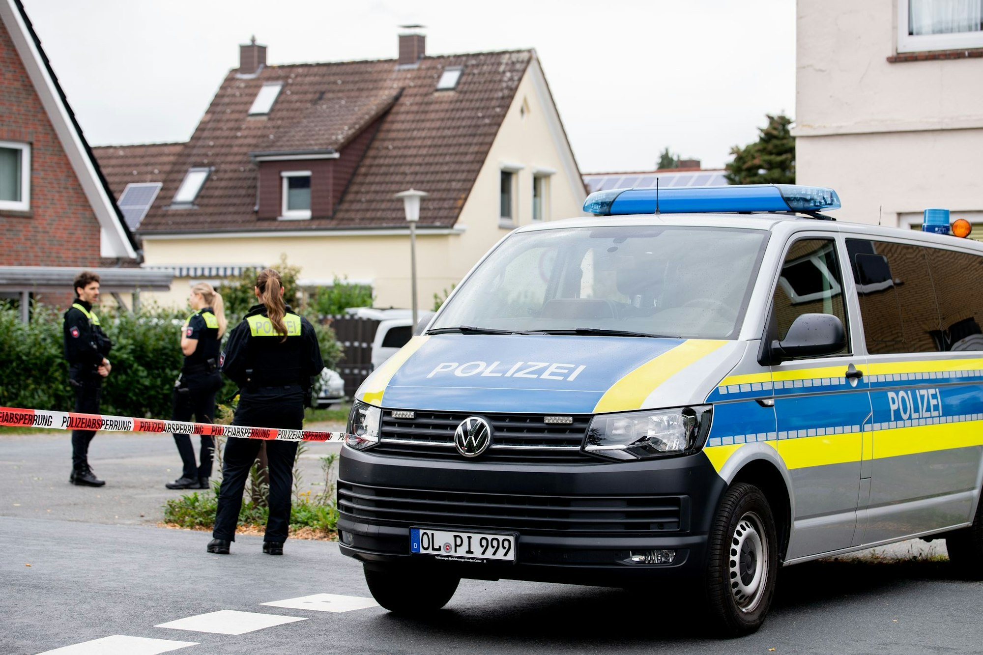 Polizisten sperren den Tatort mit Absperrband und Polizeiautos ab.
