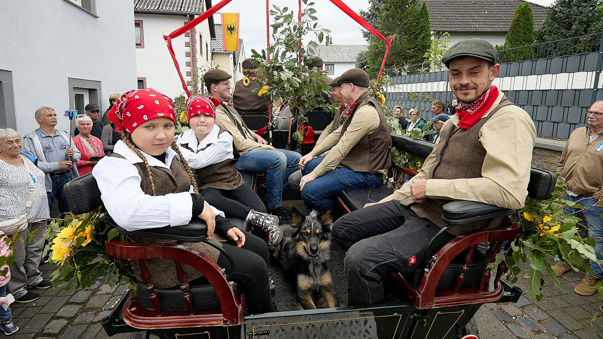 Einige Jugendliche in historischen Bauern-Kostümen sitzen in einer Pferdekutsche.