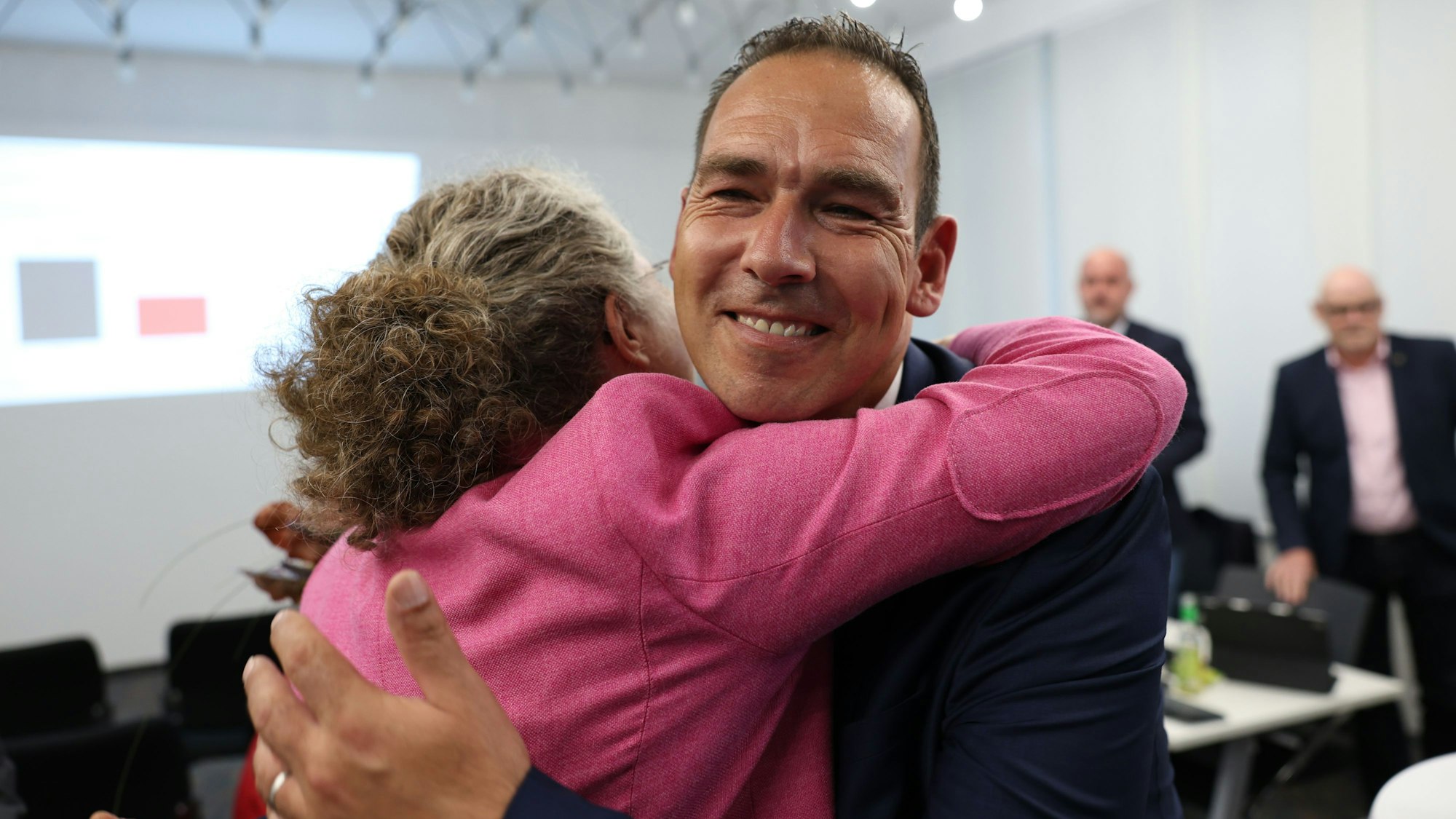 Die bisherige Bürgermeisterin von Weilerswist, Anna-Katharina Horst, ist von hinten zu sehen. Sie umarmt ihren gewählten Nachfolger Dino Steuer.