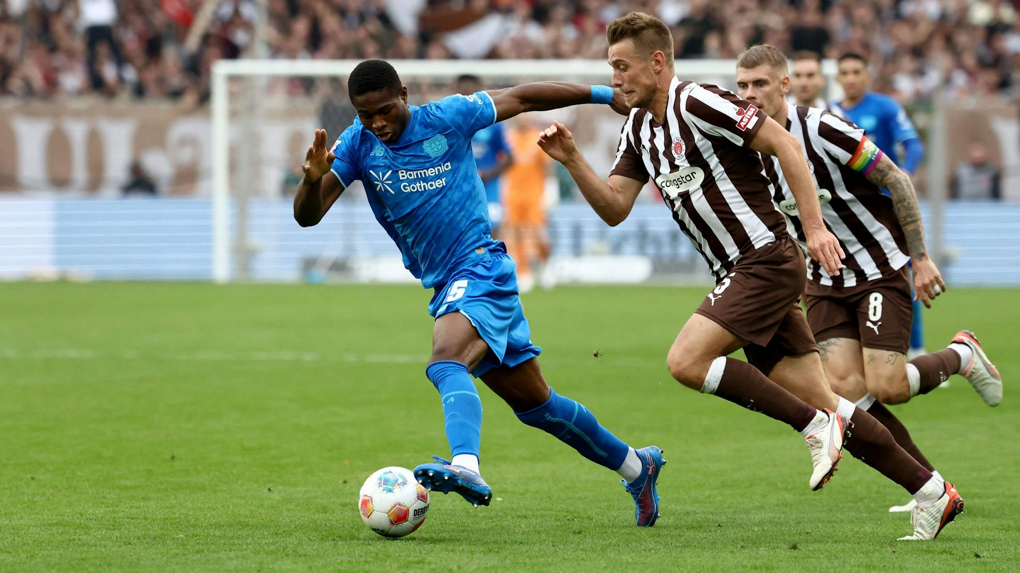 (L-R) Bayer Leverkusen's Cameroonian forward #35 Christian Kofane, St Pauli's German defender #05 Hauke Wahl and St Pauli's Swedish defender #08 Eric Smith vie for the ball during the German first division Bundesliga football match between FC St Pauli and Bayer 04 Leverkusen in Hamburg, northern Germany on September 27, 2025. (Photo by Ibrahim OT / AFP) / DFL REGULATIONS PROHIBIT ANY USE OF PHOTOGRAPHS AS IMAGE SEQUENCES AND/OR QUASI-VIDEO