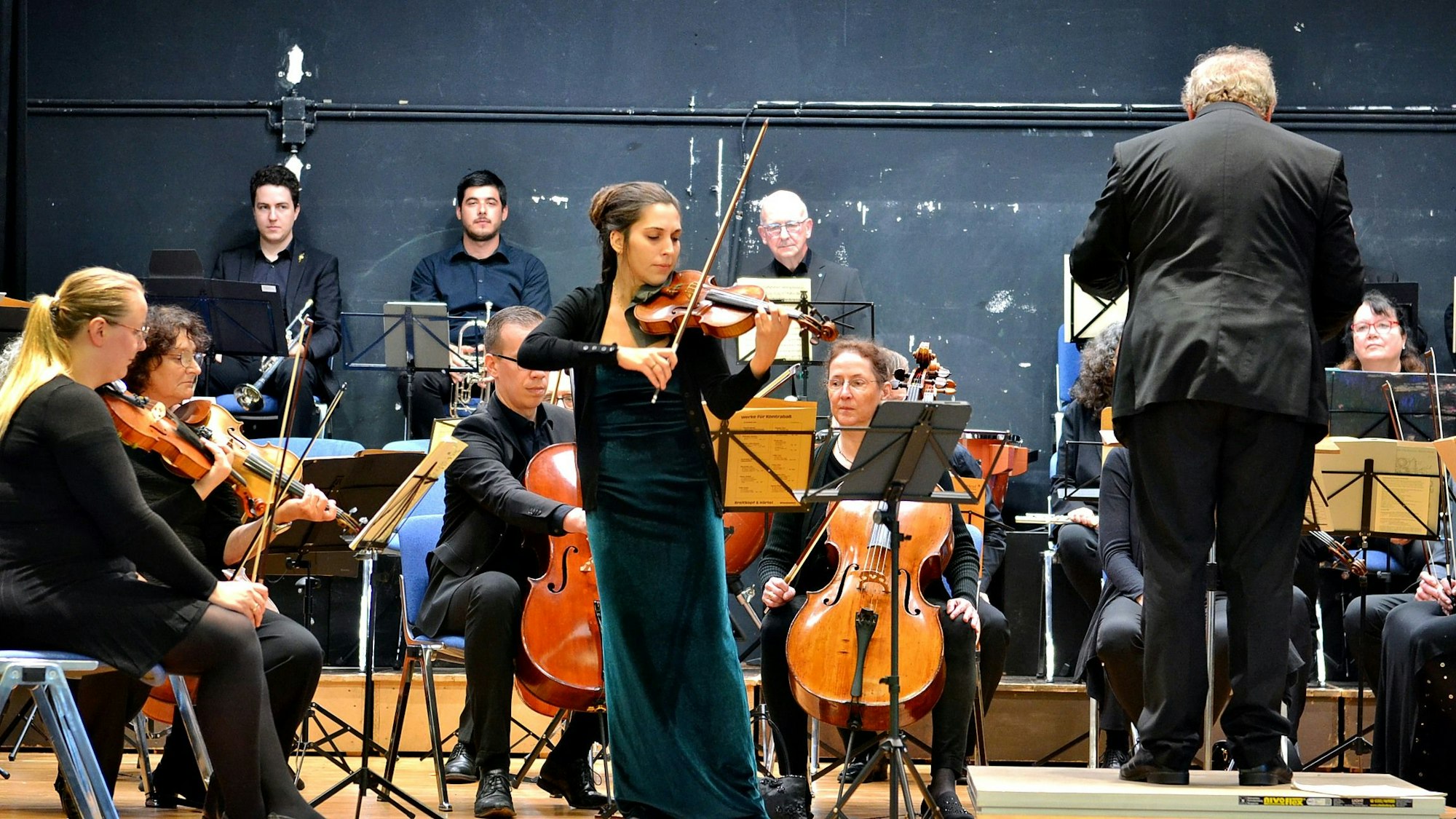 Das Bild zeigt Musikerinnen, Musiker und den Dirigenten auf der Bühne.