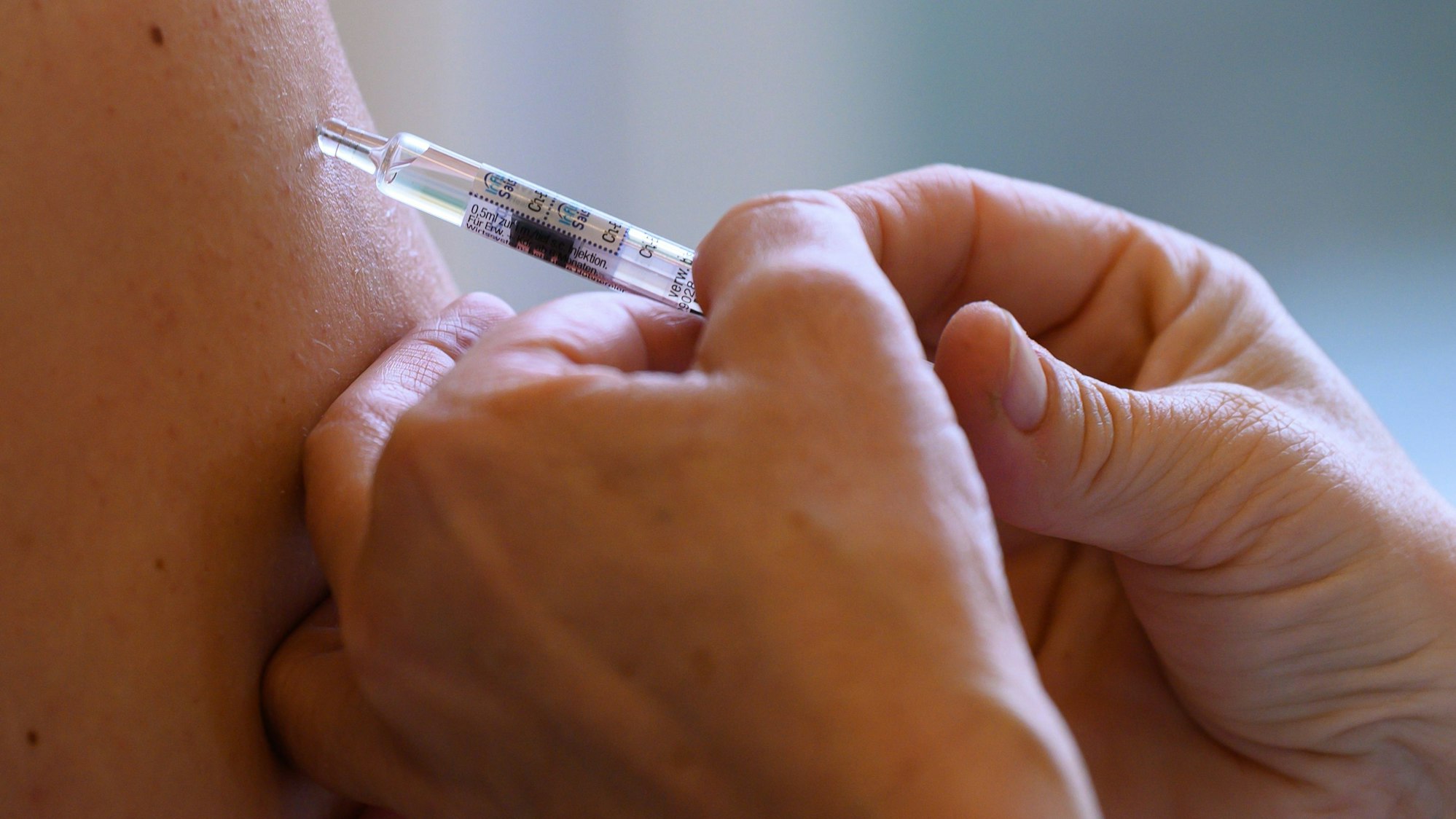 Eine Ärztin impft mit dem saisonalen Wirkstoff gegen die Grippe.
