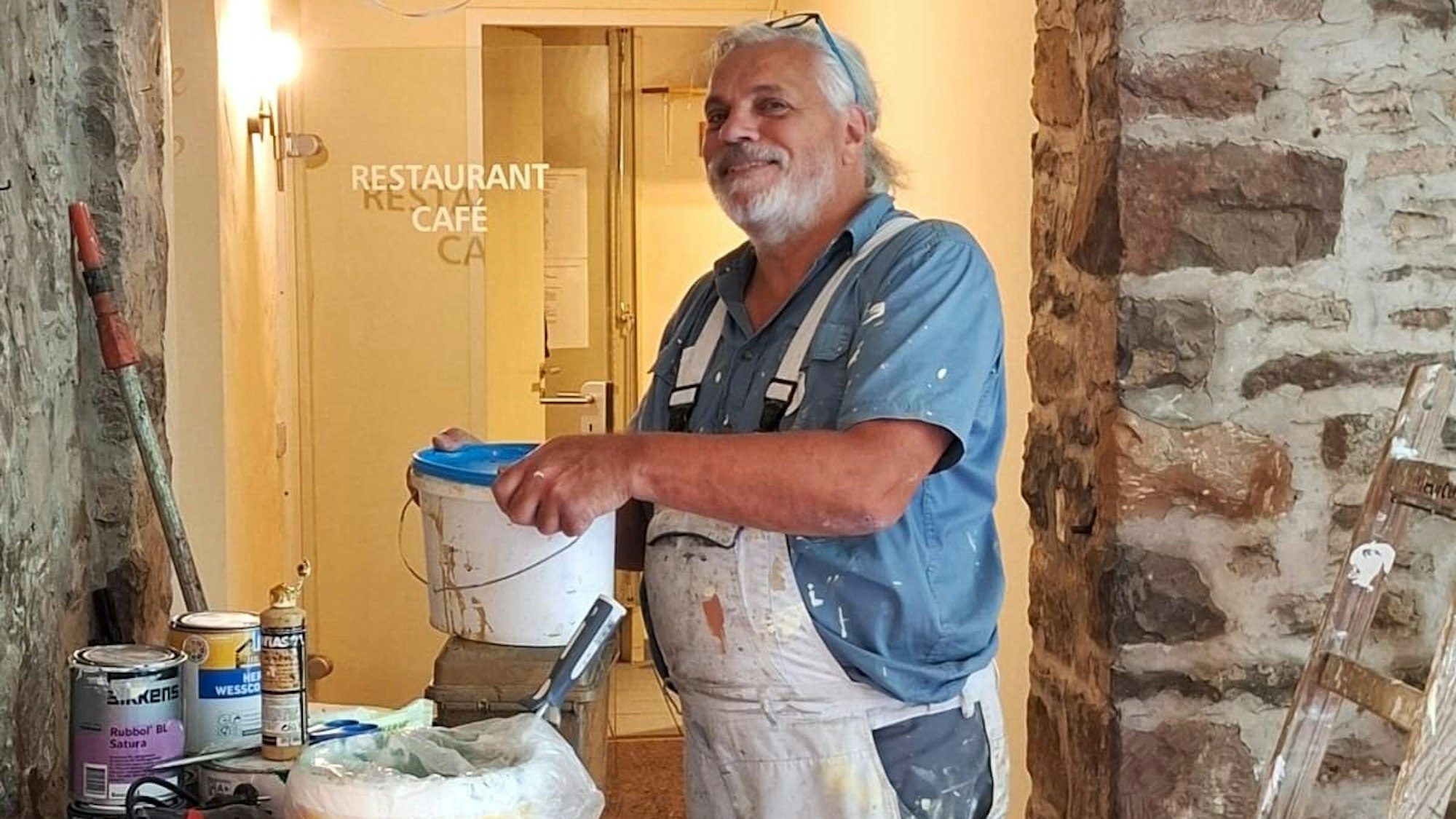 Alessio Nalesini steht in Malerklamotten an einem Tisch mit Farbeimern.