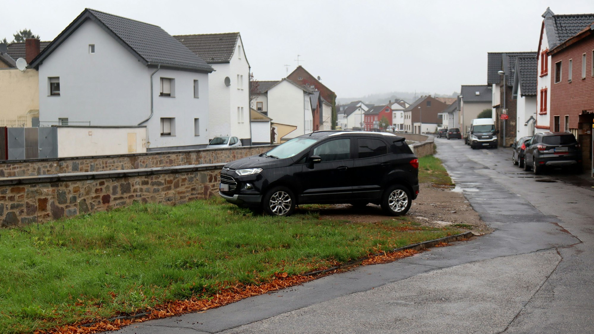Ein Auto steht auf einem unbefestigten Platz einer Wiese an der Erftmauer in Arloff.