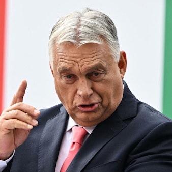 Der ungarische Ministerpräsident Viktor Orbán steht vor einer Fahne seines Landes und hält eine Rede.