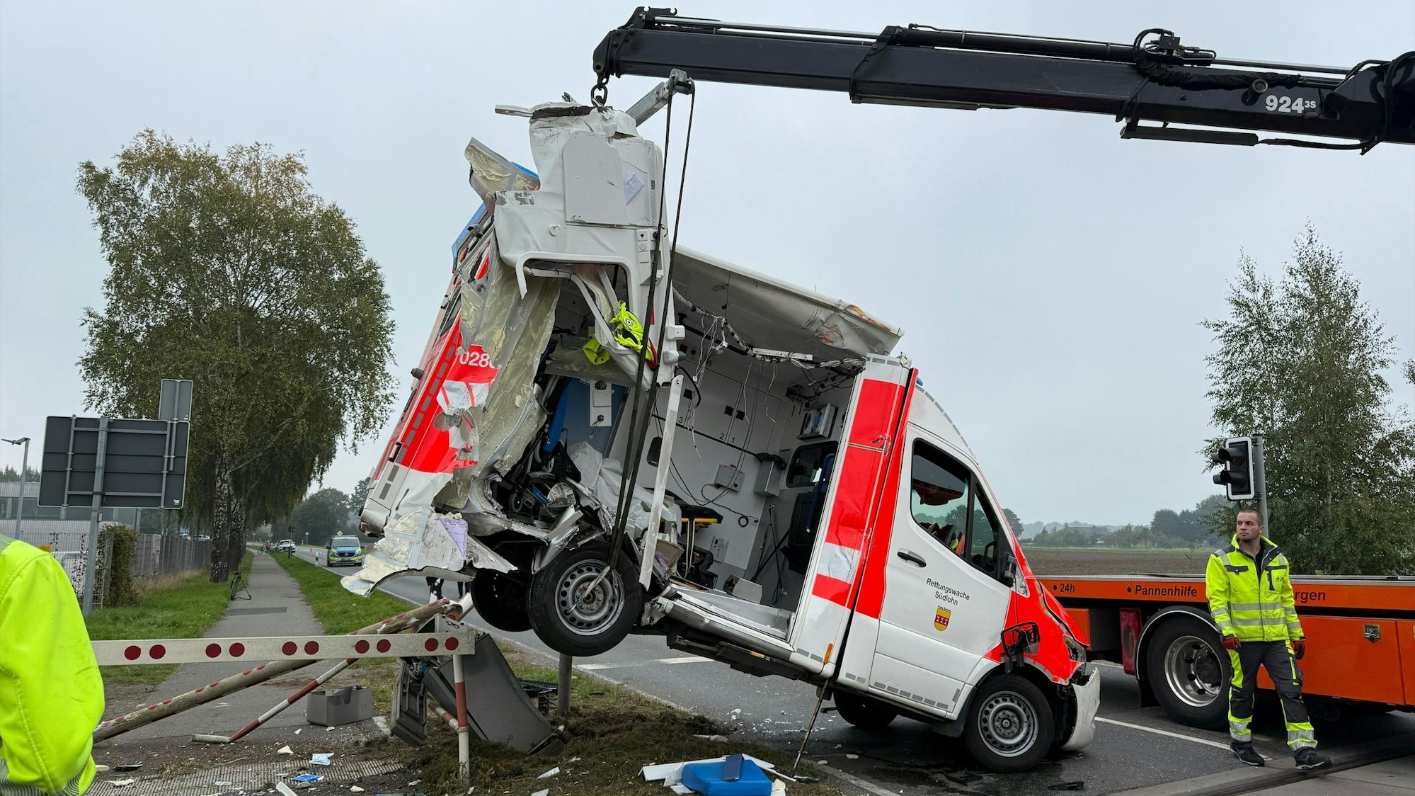 Ein Rettungswagen wird durch einen Kran geborgen. Der Wagen ist an einem Bahnübergang mit einem Regionalzug kollidiert.