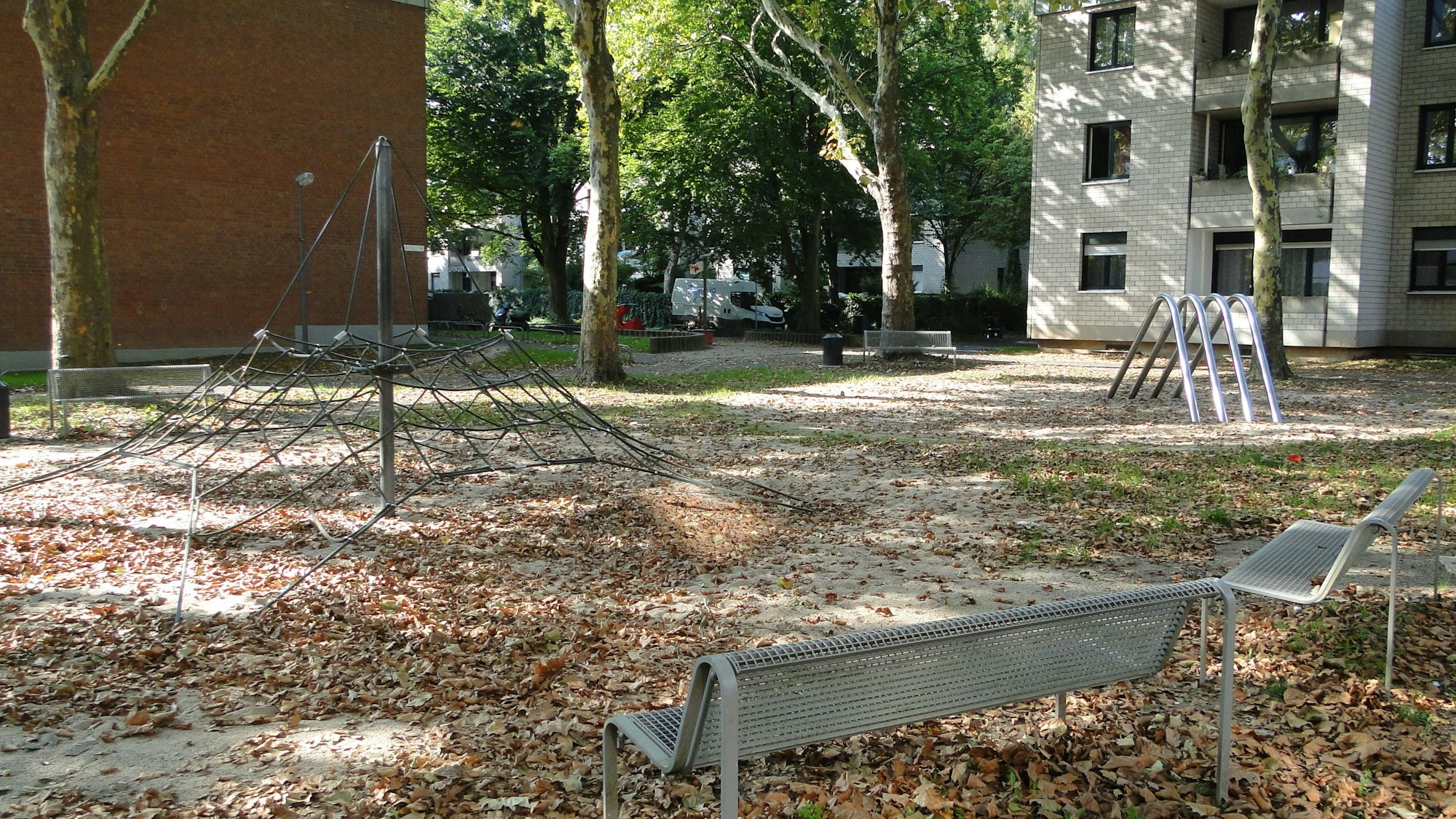 Zwei Bänke, und ein Spinnennetz stehen auf einem Spielplatz.
