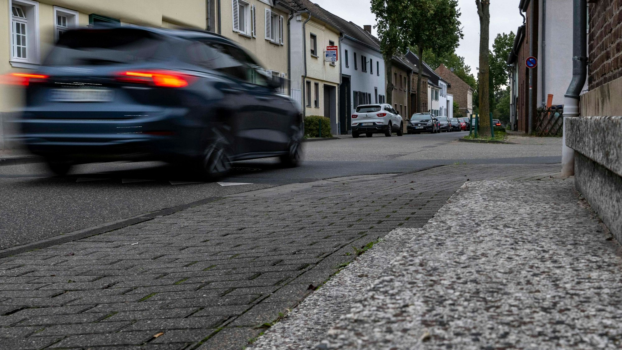 Das Bild zeigt ein Auto, das durch eine Dorfstraße fährt.