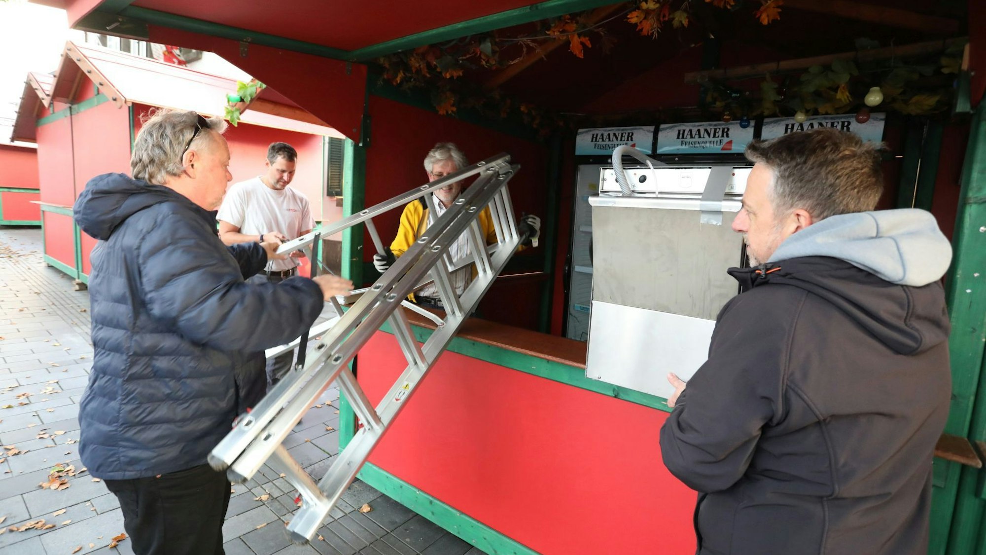 Ein Mann reicht eine Leiter an einen Kollegen in einer der Weinbuden weiter.