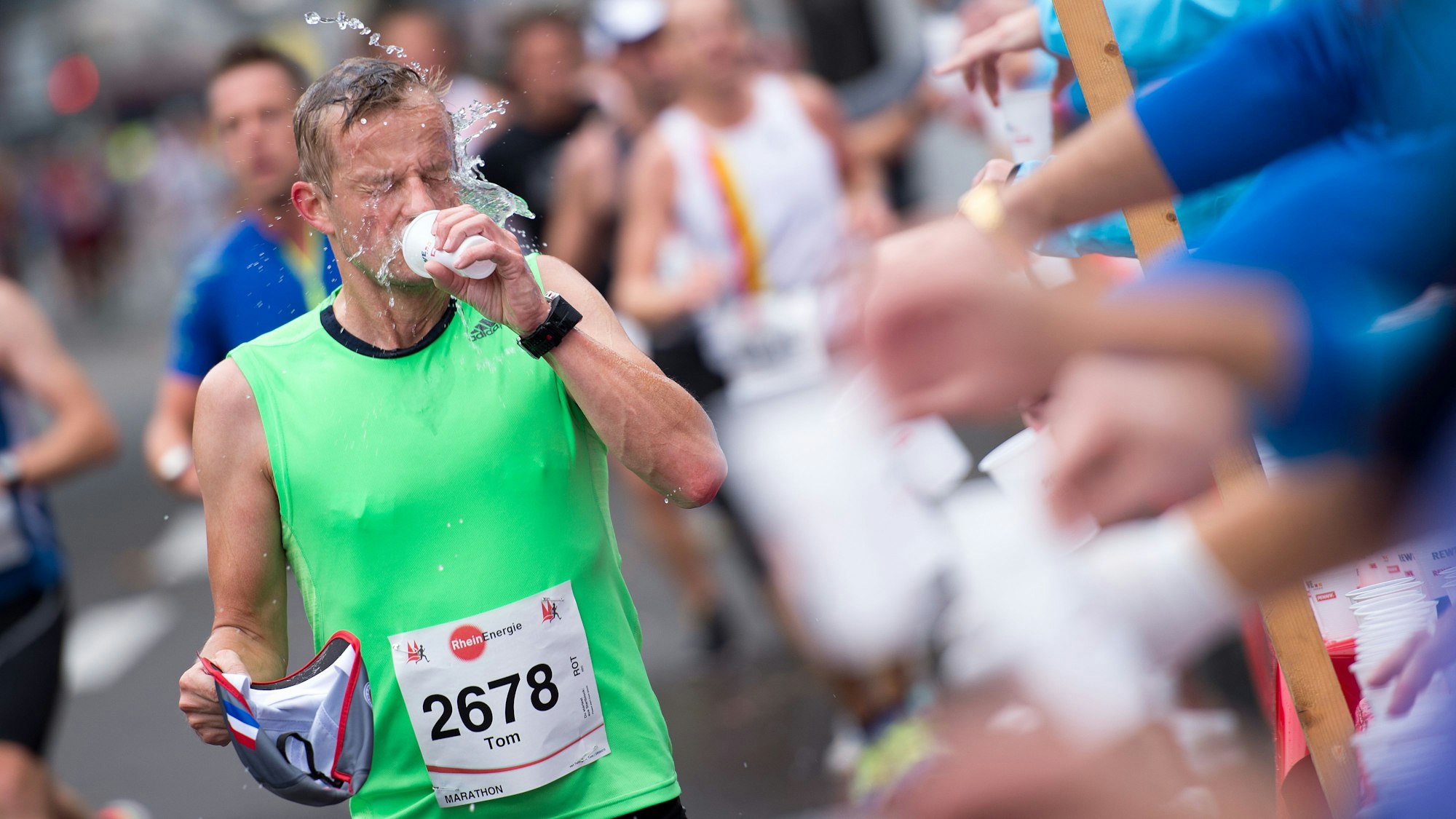 Ein Läufer schüttet sich am beim Marathon in Köln (Nordrhein-Westfalen) an einer Verpflegungsstelle Wasser ins Gesicht.