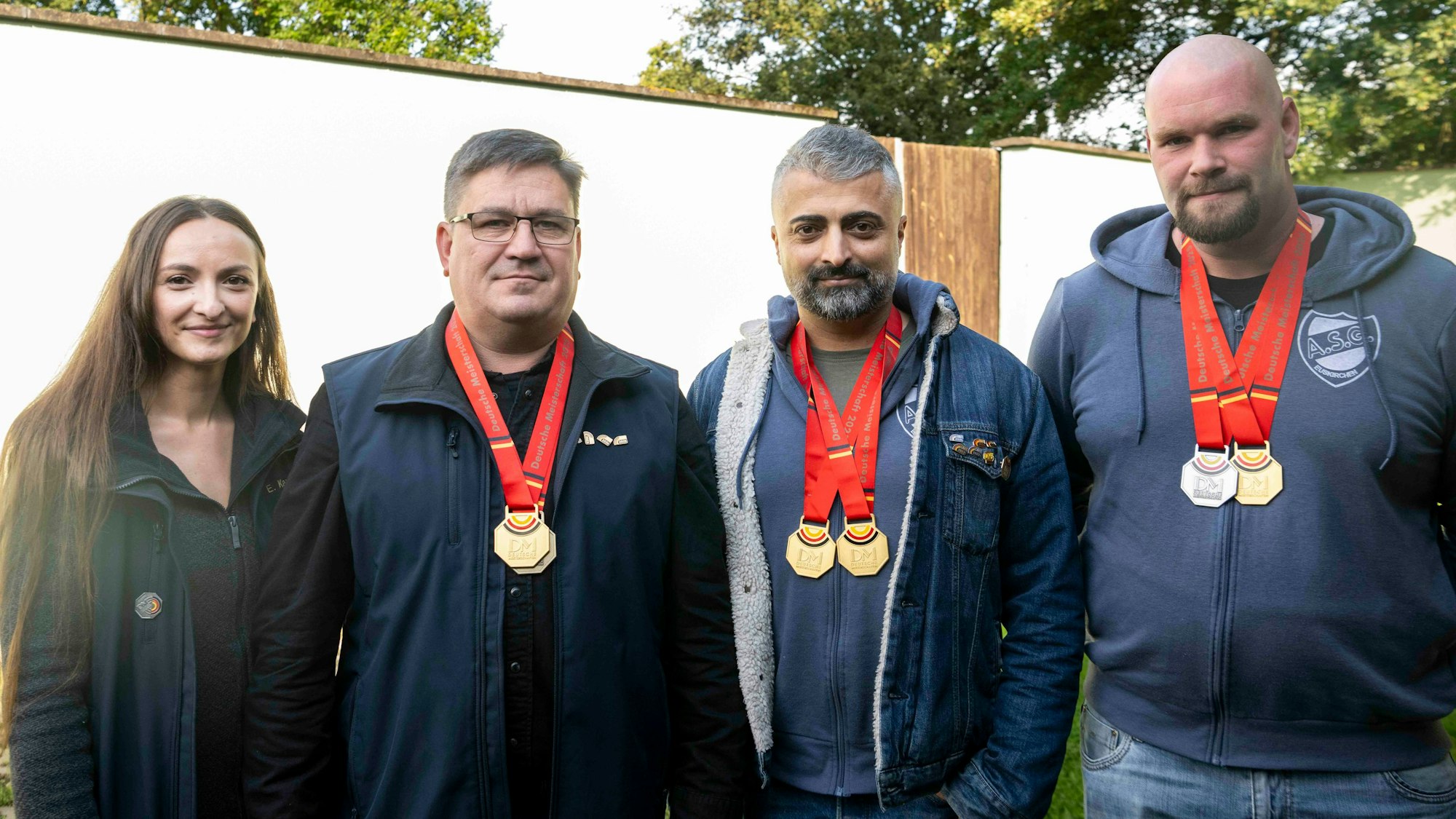 Die drei Männer neben Elena Kapp tragen Medaillen.