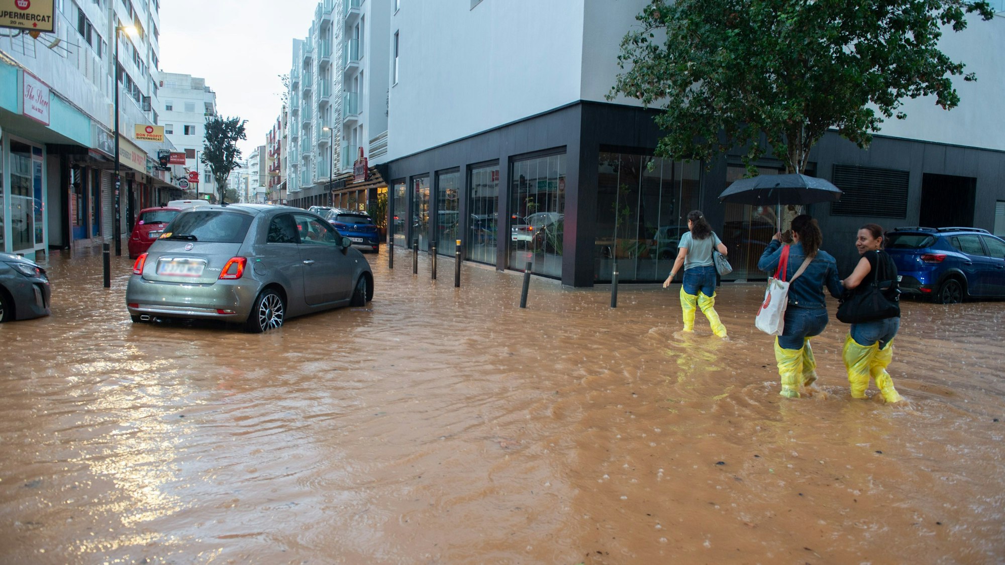 Menschen gehen eine überflutete Straße entlang.