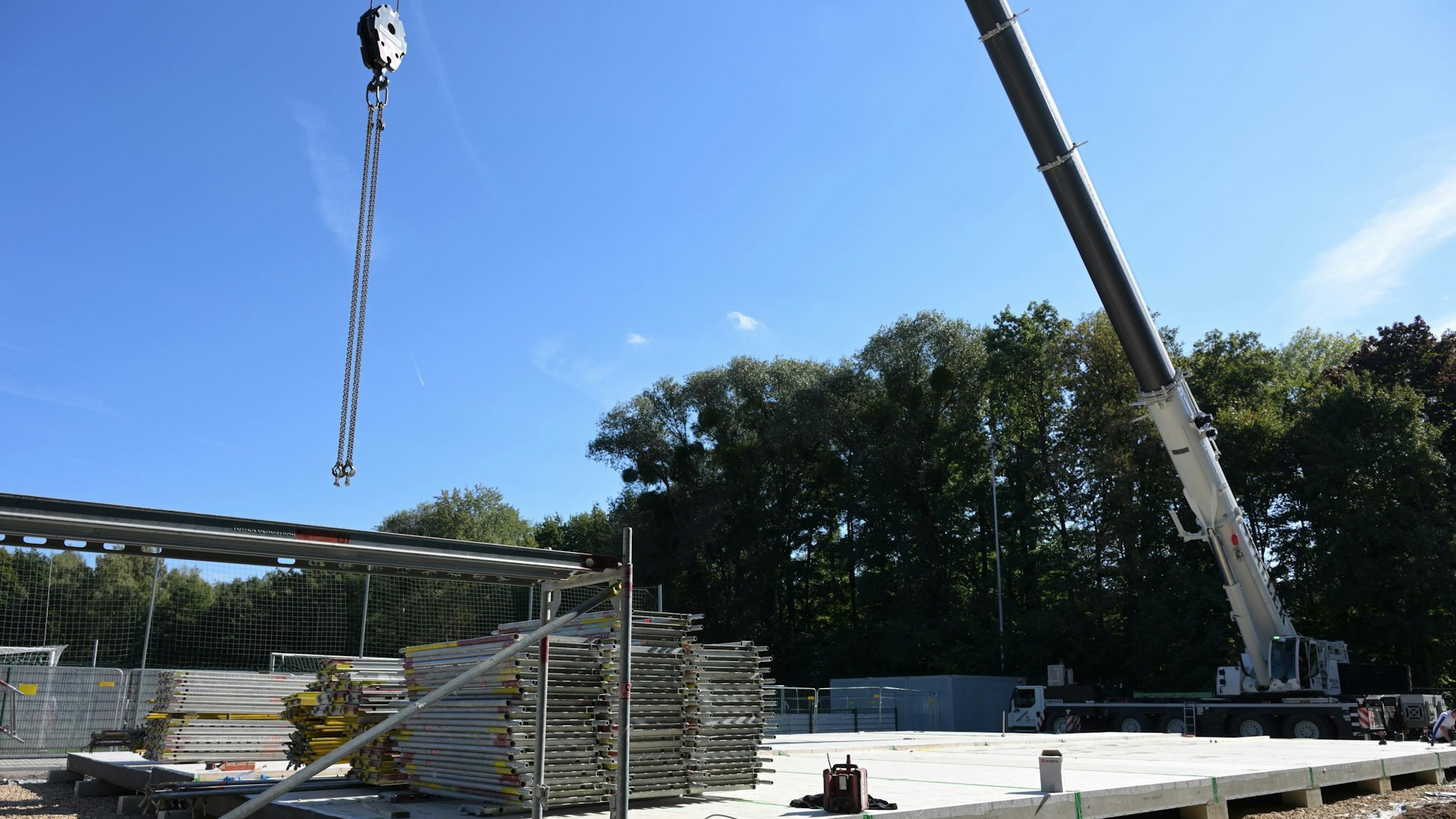 Man sieht einen Kran und die Bodenplatte aus Beton.