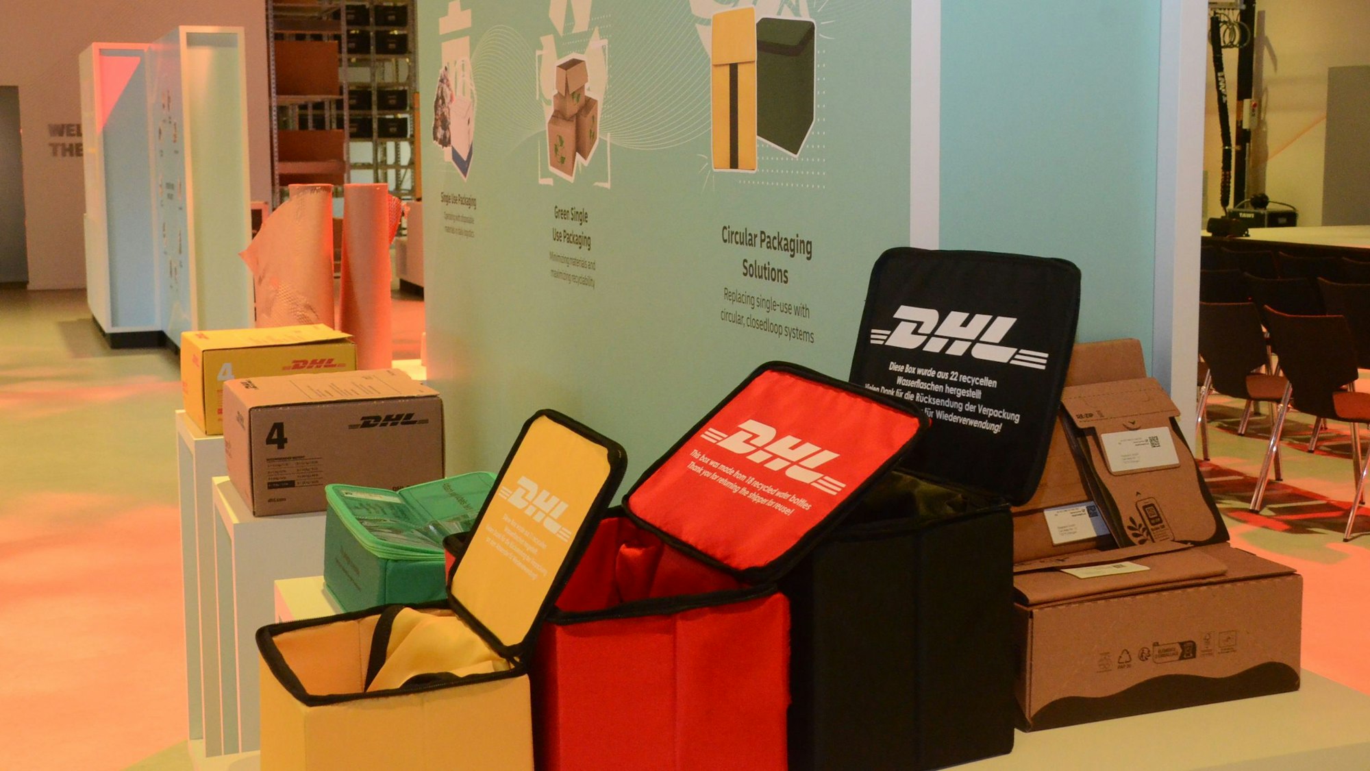 Boxen mit dem Aufdruck DHL in Rot, Grün, Gelb und Schwarz.