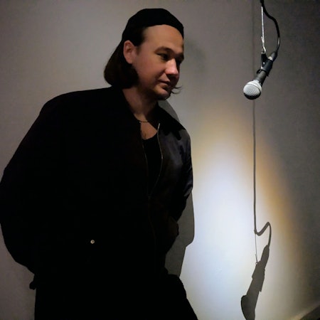 Ein Mann steht in einem dunklen Raum an einem Mikrofon