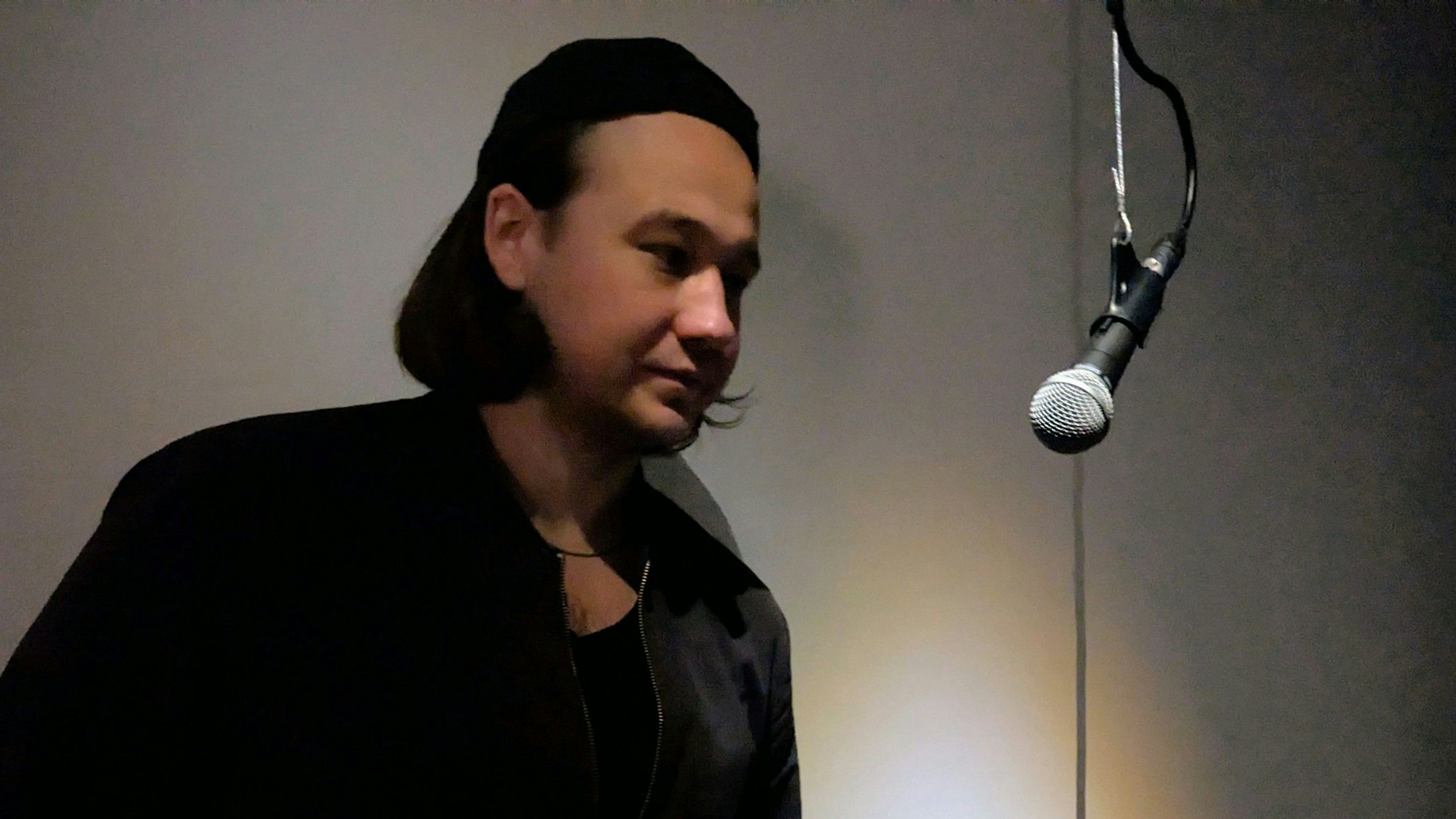 Ein Mann steht in einem dunklen Raum an einem Mikrofon