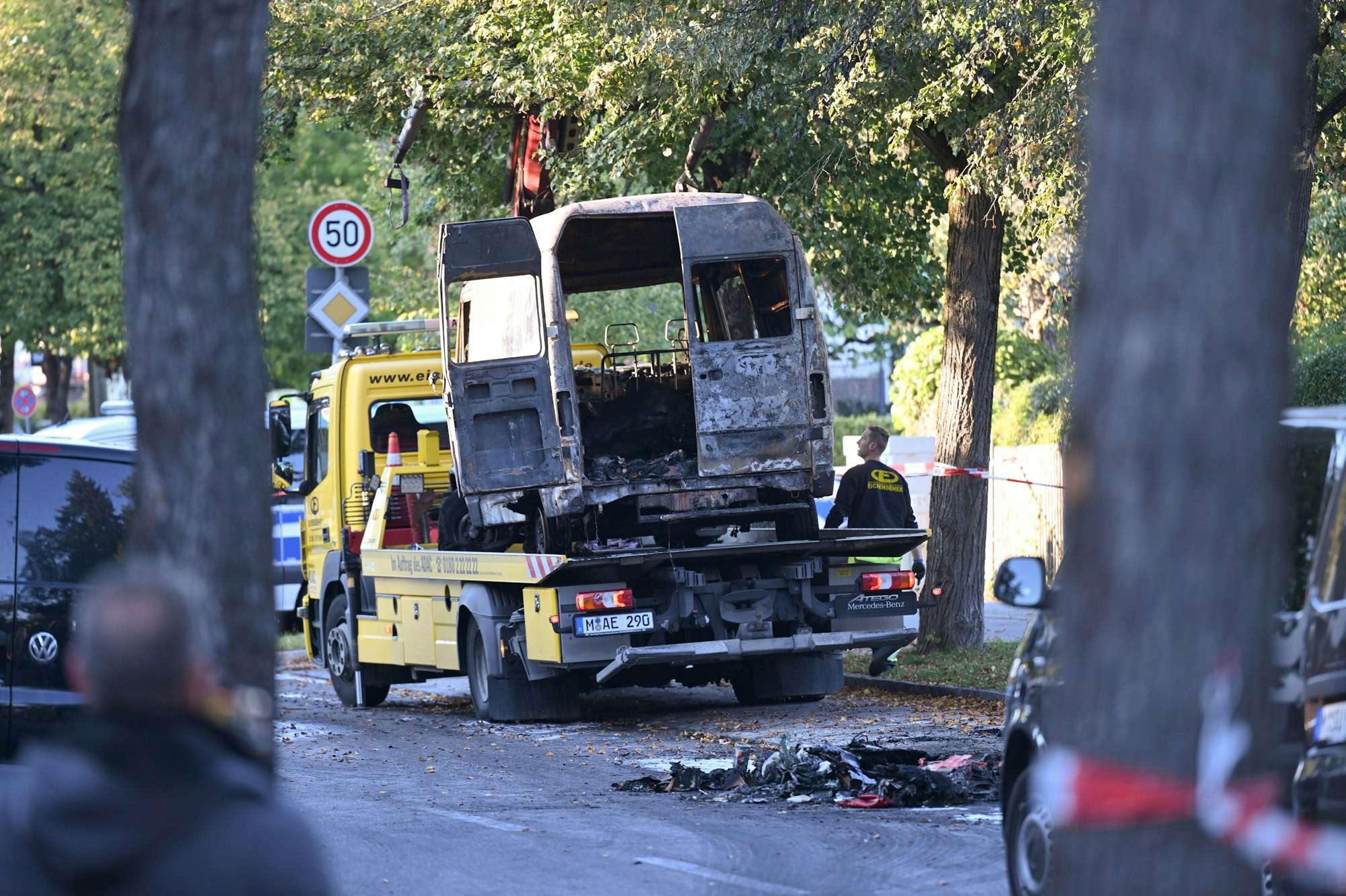 01.10.2025, Bayern, München: Ein ausgebrannter Transporter wird nach einem Brand in einem Einfamilienhaus im Münchner Stadtteil Lerchenau abtransportiert. Die Polizei geht derzeit von einem privaten Hintergrund aus. Ein 57-jähriger Mann aus Starnberg soll das Haus im Münchner Norden angezündet und Sprengfallen deponiert haben. Foto: Felix Hörhager/dpa +++ dpa-Bildfunk +++
