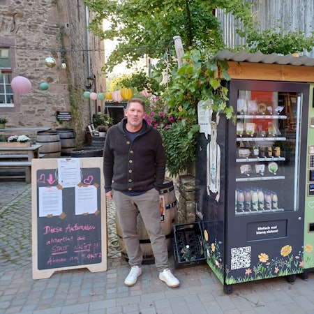 Michael Starkel steht zwischen den „Eifelmaten“ sowie der Tafel, auf der das Schreiben der Stadt Bad Münstereifel klebt.