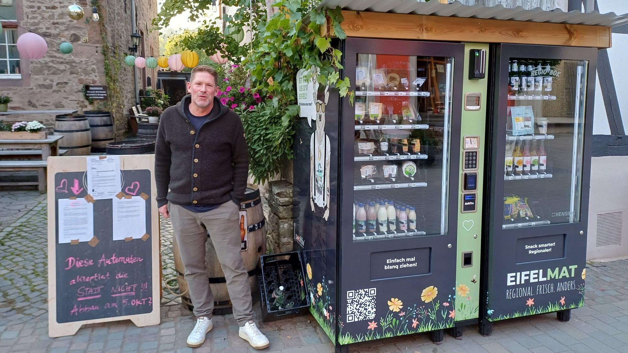 Michael Starkel steht zwischen den „Eifelmaten“ sowie der Tafel, auf der das Schreiben der Stadt Bad Münstereifel klebt.