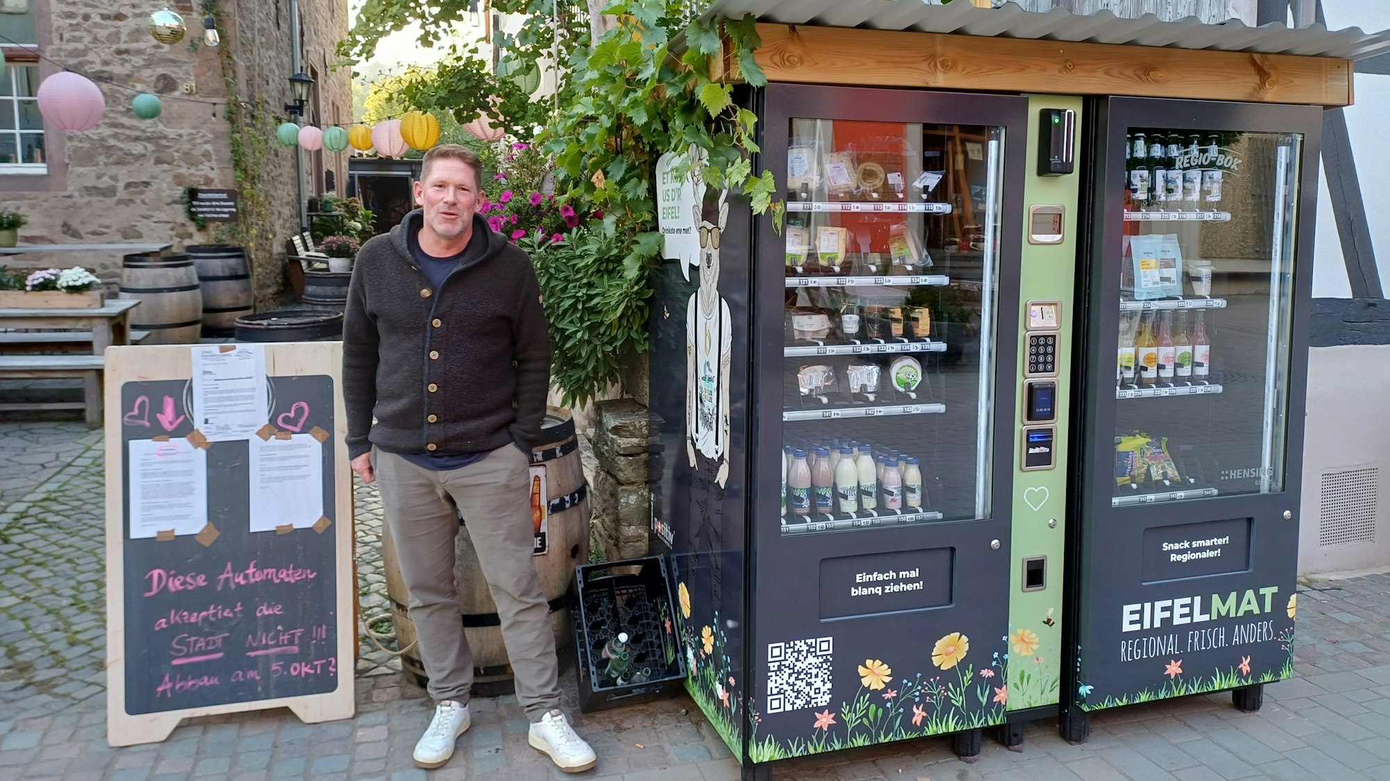 Michael Starkel steht zwischen den „Eifelmaten“ sowie der Tafel, auf der das Schreiben der Stadt Bad Münstereifel klebt.