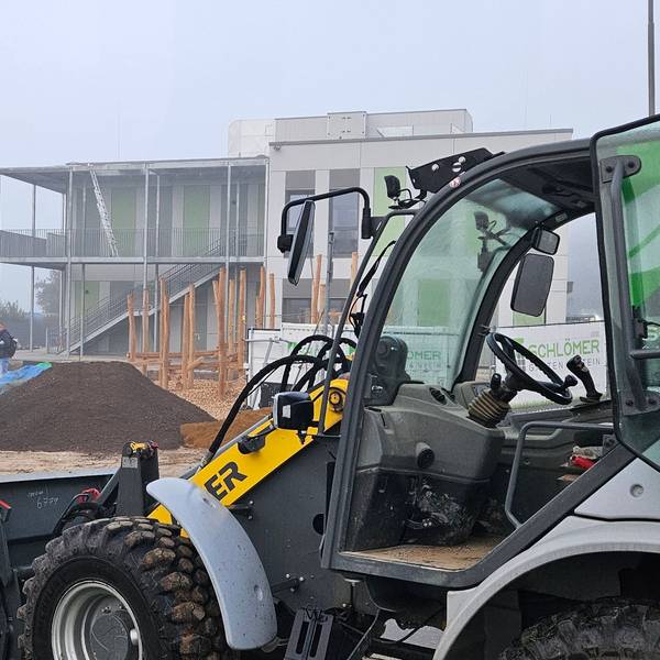 Zu sehen ist die Baustelle für einen Kindergarten mit einem Radlader und einem kleinen Bagger.