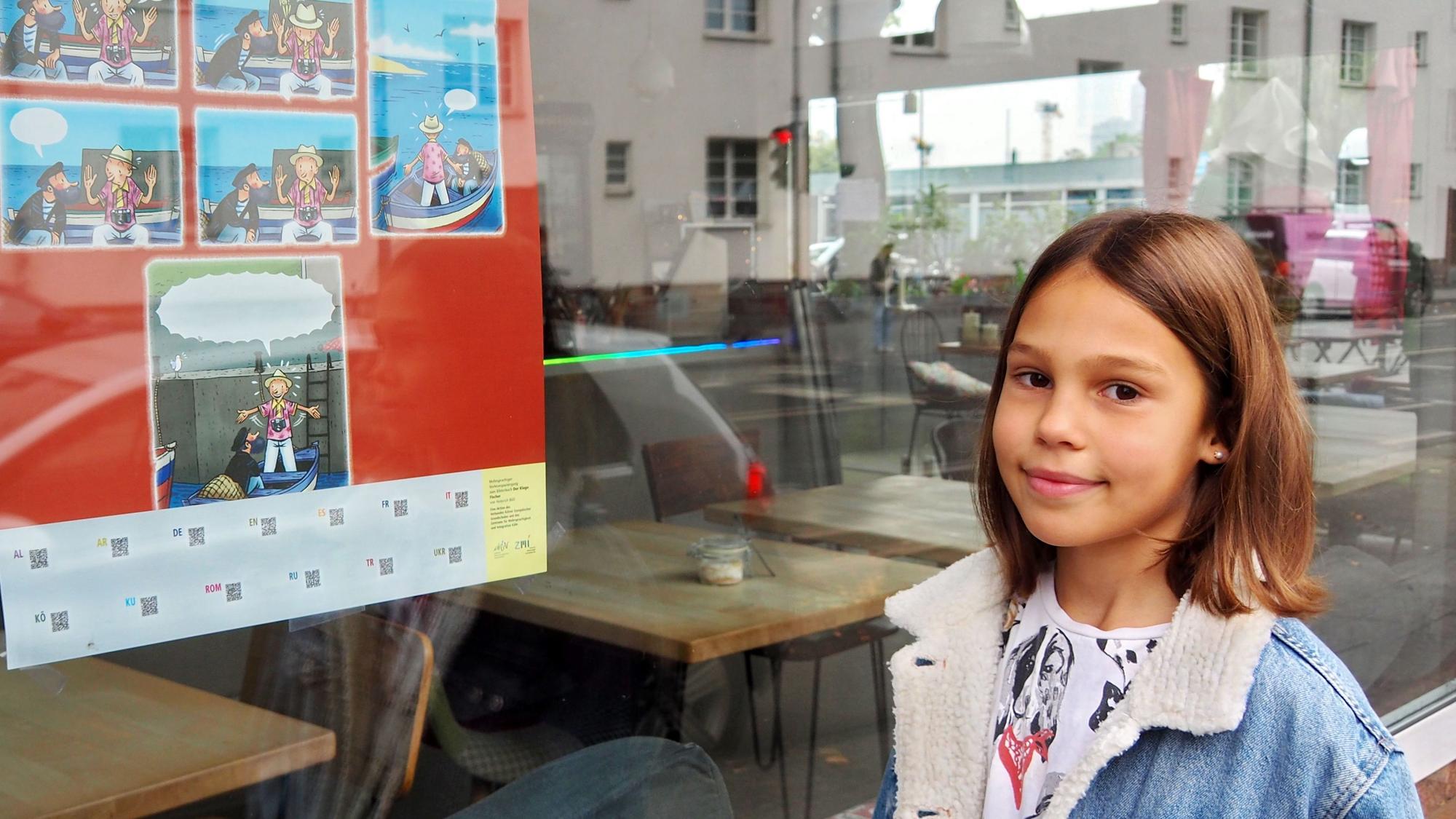 Ein Mädchen steht vor dem Fenster eines Cafés. Darin hängt ein Plakat mit dem Hinweis auf den Vorlesespaziergang.