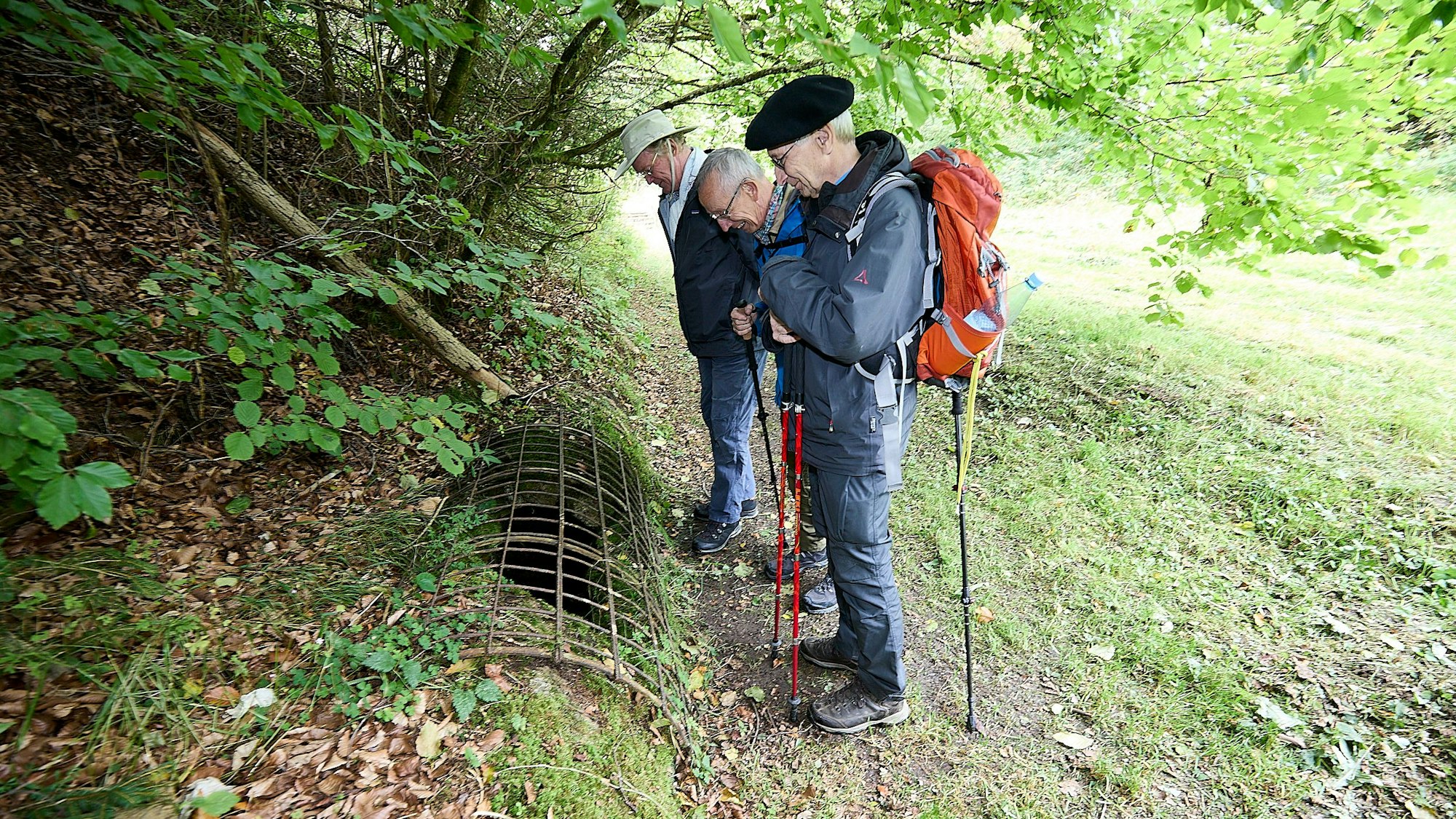 Drei ältere Männer schauen auf ein Überbleibsel des Römerkanals.