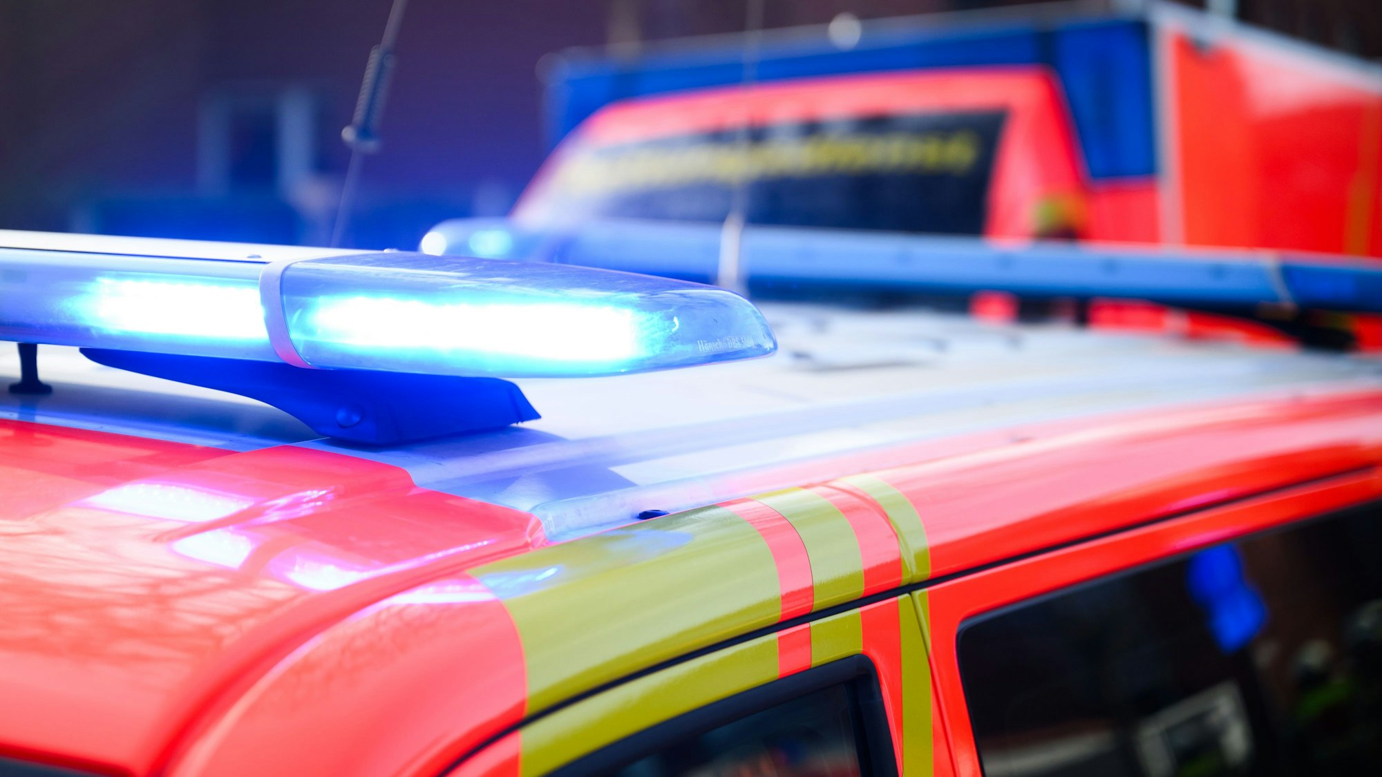 Blaulichter leuchten an einer Einsatzstelle auf einem Notarzt-Fahrzeug und einem Rettungswagen.