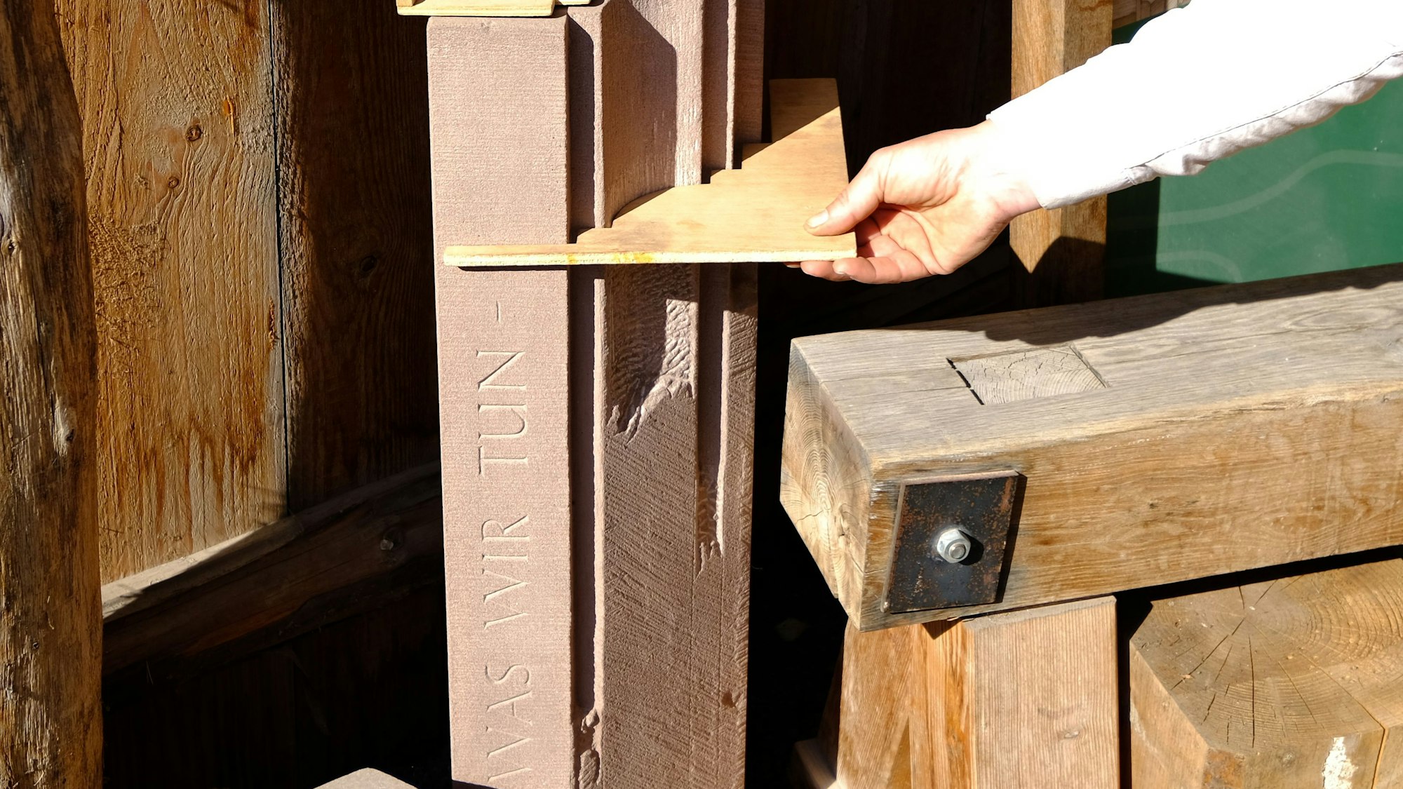 Die Steinmetzmeisterin hält eine hölzerne Schablone an die Gerichtssäule.