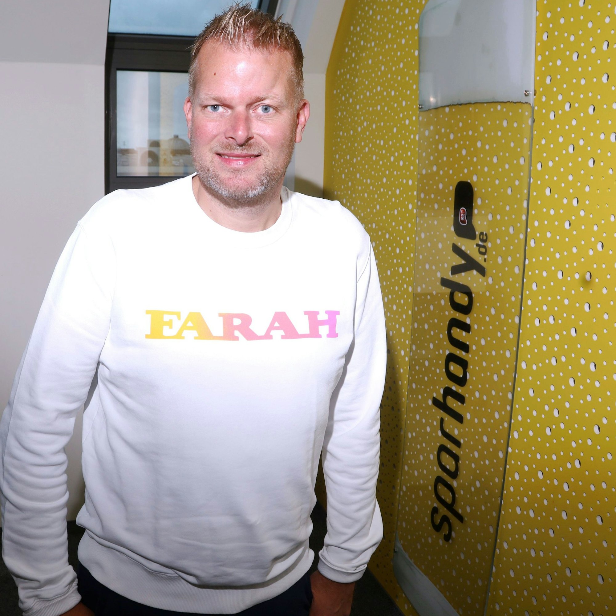 Wilke Stroman ist neben einem großen Logo-Schild zu sehen, auf dem sparhandy.de steht.