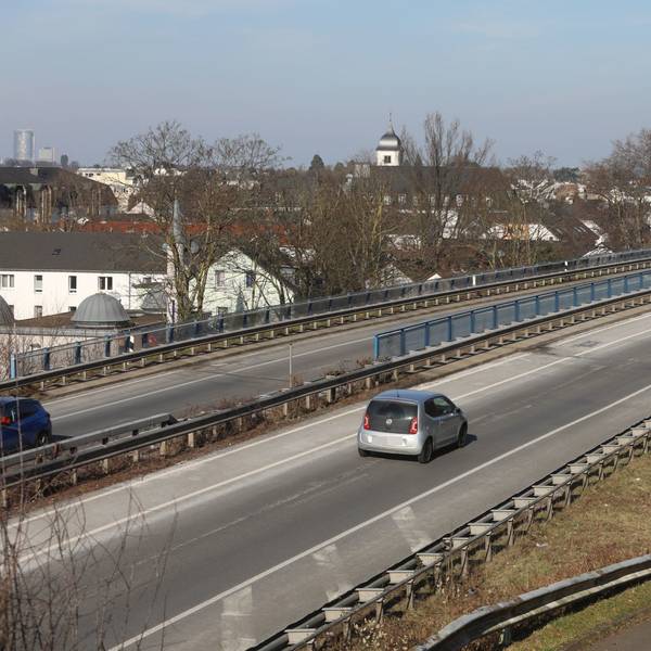 Autos fahren über eine Brücke, im Hintergrund die Altstadt von Königswinter.