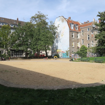 Eine große Sandfläche wird von Rasenflächen eingefasst.