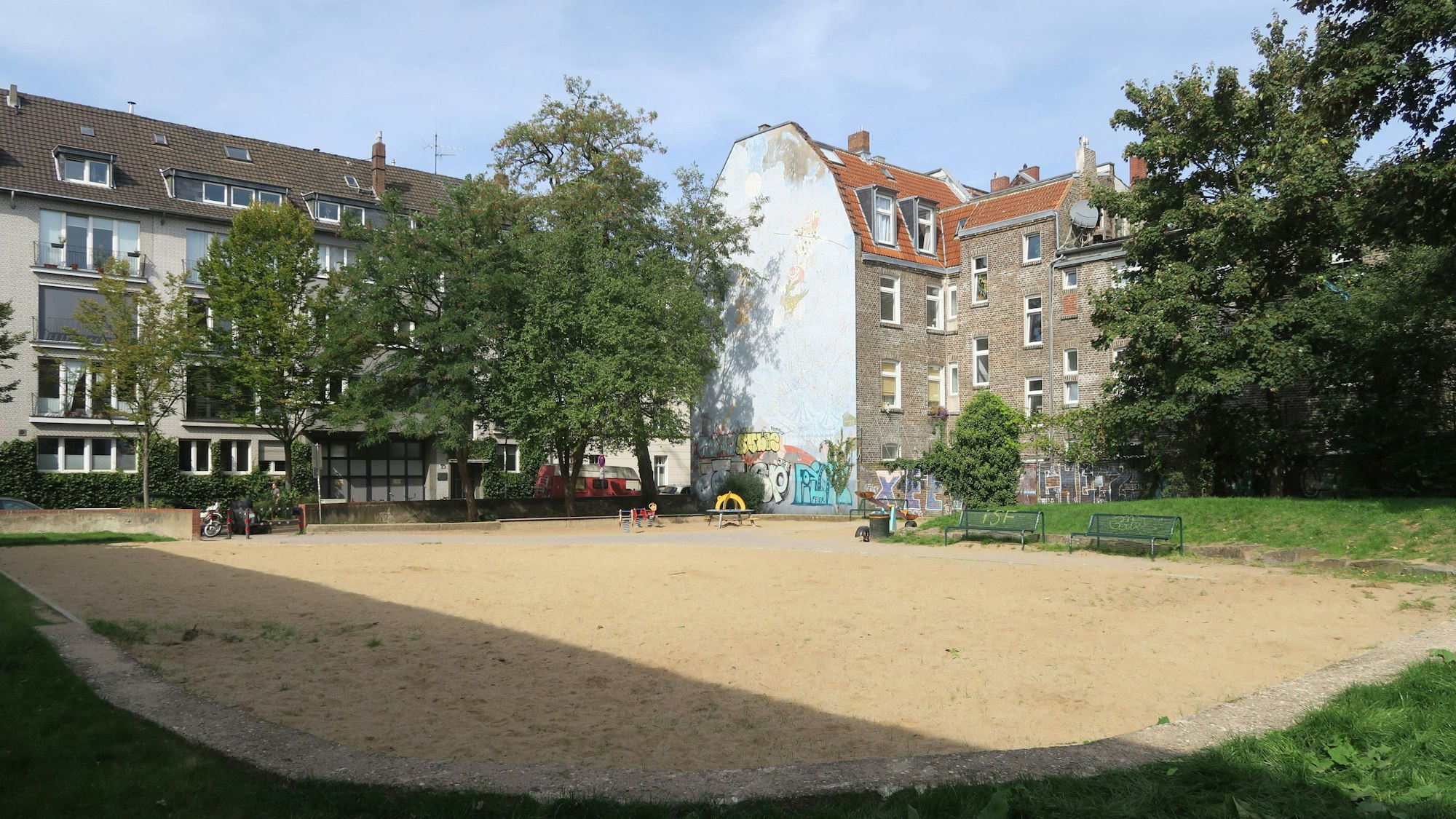 Eine große Sandfläche wird von Rasenflächen eingefasst.