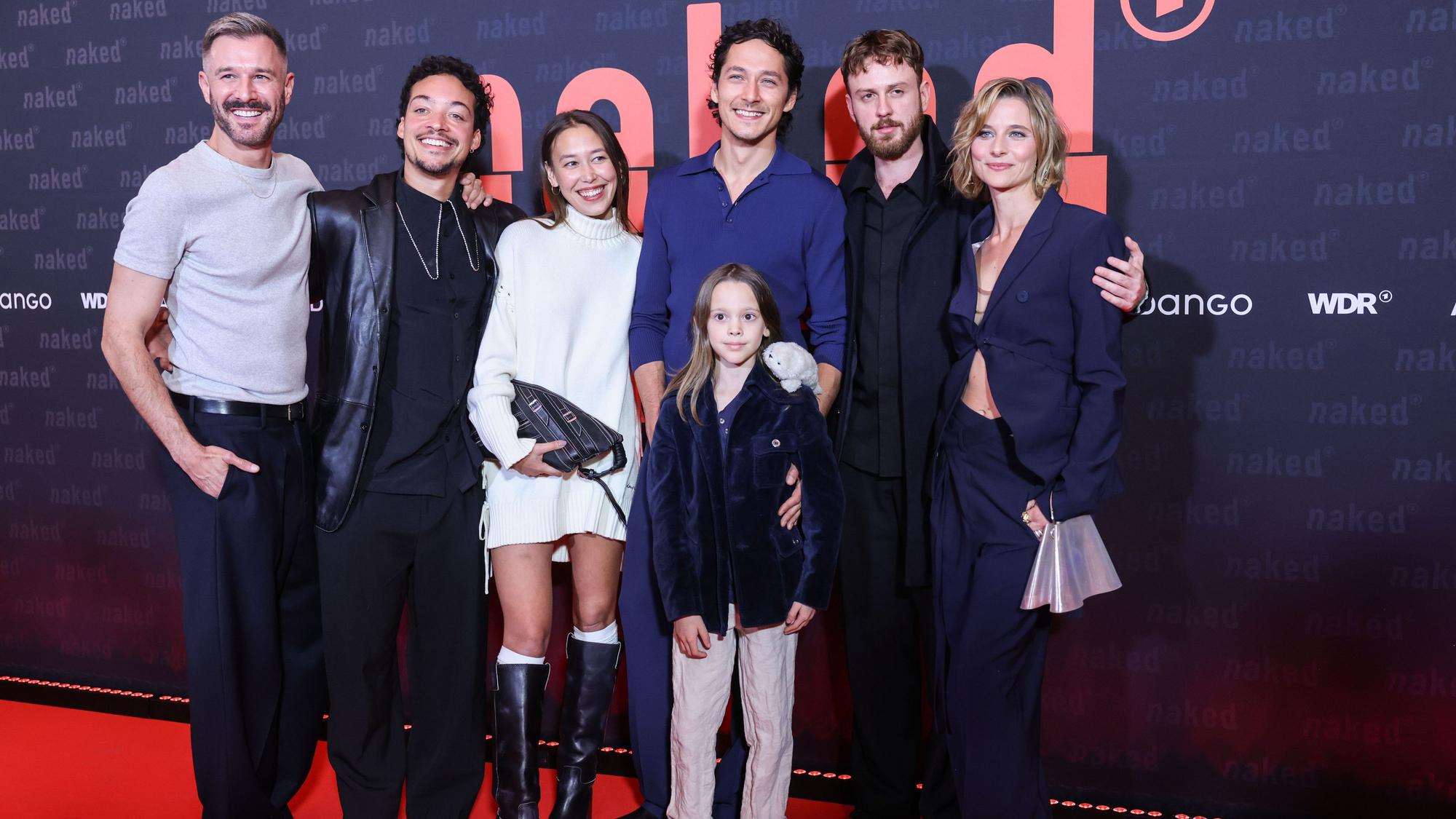 Die Schauspieler Jochen Schopp (Julian, l-r), Aurel Mertz (David), Malaya Stern Takeda (Lilith), Noah Saavedra (Luis), Thore Anker (vorn), Marco Gianni (Johann) und Svenja Jung (Marie) stehen vor der Premiere der ARD/WDR-Serie ‚naked‘ auf dem roten Teppich.