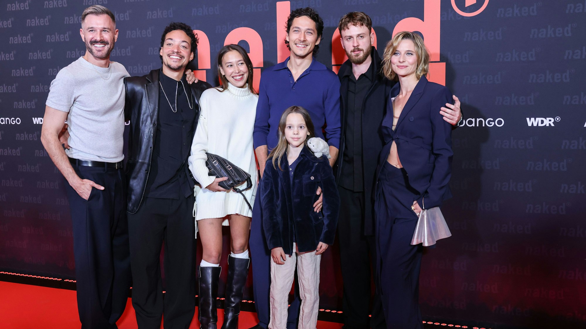 Die Schauspieler Jochen Schopp (Julian, l-r), Aurel Mertz (David), Malaya Stern Takeda (Lilith), Noah Saavedra (Luis), Thore Anker (vorn), Marco Gianni (Johann) und Svenja Jung (Marie) stehen vor der Premiere der ARD/WDR-Serie ‚naked‘ auf dem roten Teppich.