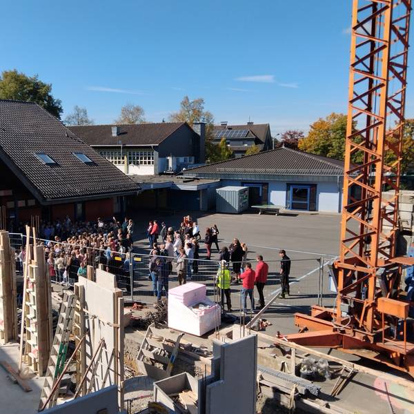 Beim Richtfest der Grundschule Much-Marienfeld sangen die Kinder ein Lied. Das erste Gebäude steht im Rohbau, das zweite wächst auf dem Schulhof.