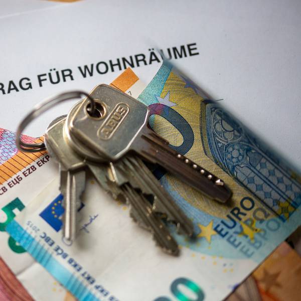 Ein Mietvertrag für Wohnräume liegt zusammen mit Geldscheinen und Wohnungsschlüsseln auf einem Tisch.