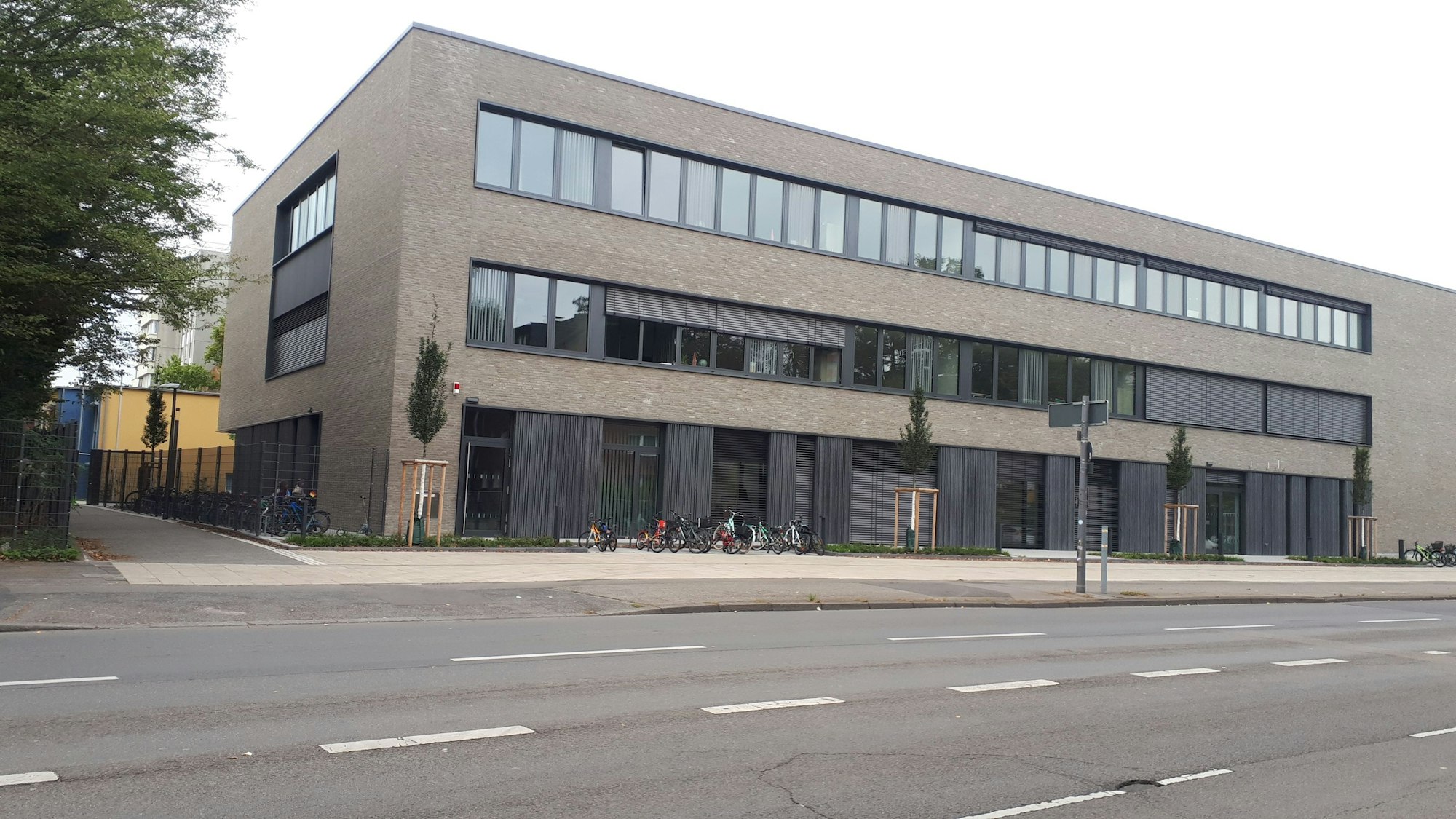 Ein dreistöckiges flaches Gebäude steht an einer mehrspurigen Straße.