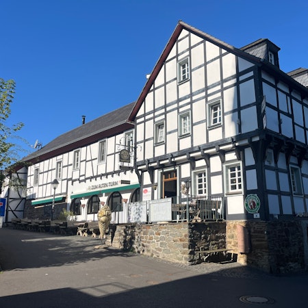 Die Gaststätte „Zum Alten Turm“ in Hennef-Stadt Blankenberg steht direkt gegenüber des Katharinenturms, dessen Schatten auf das Fachwerkhaus fällt.