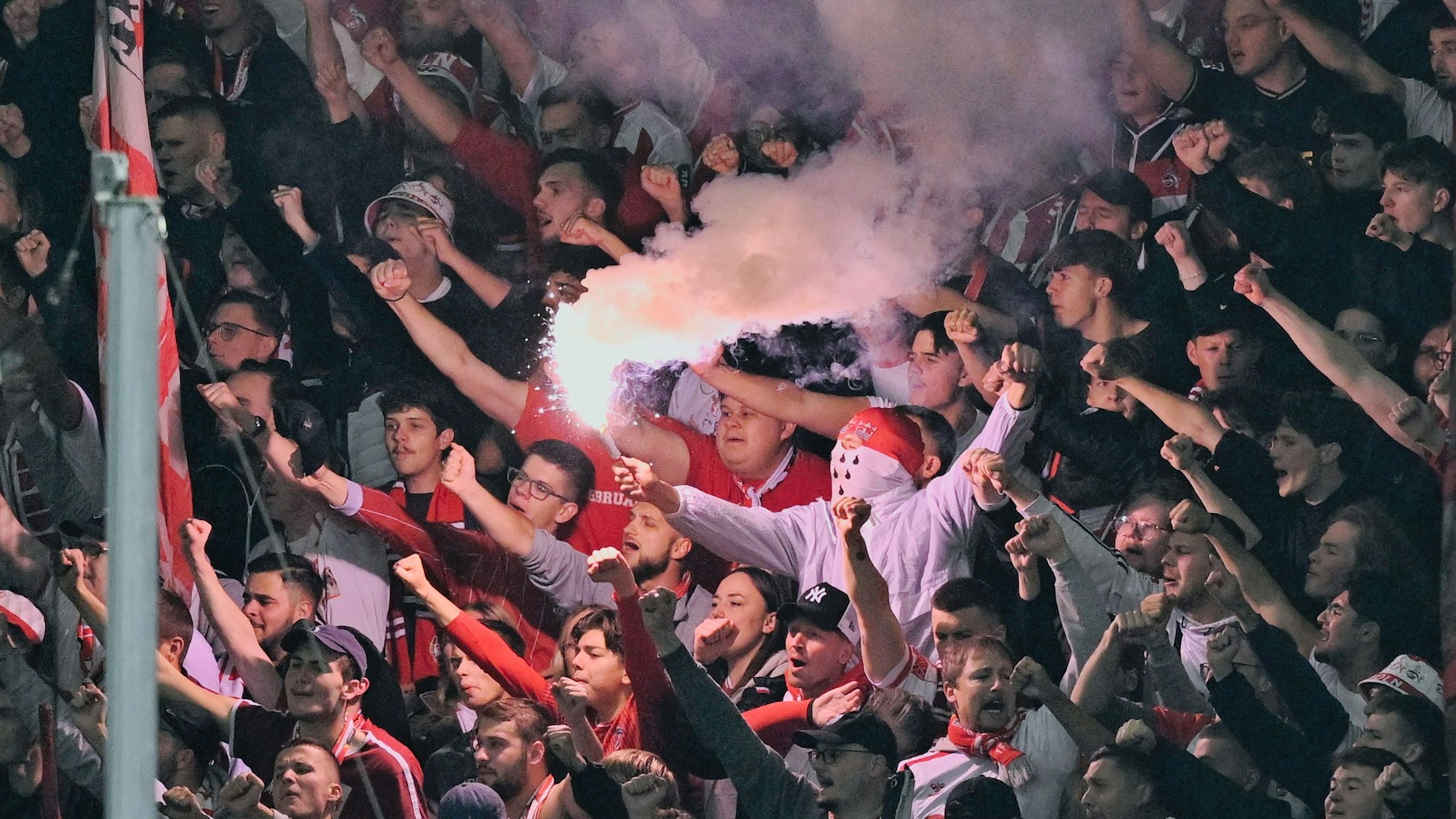 Ein Fan des 1. FC Köln hält am 3. Oktober in Hoffenheim ein bengalisches Feuer in der Hand.