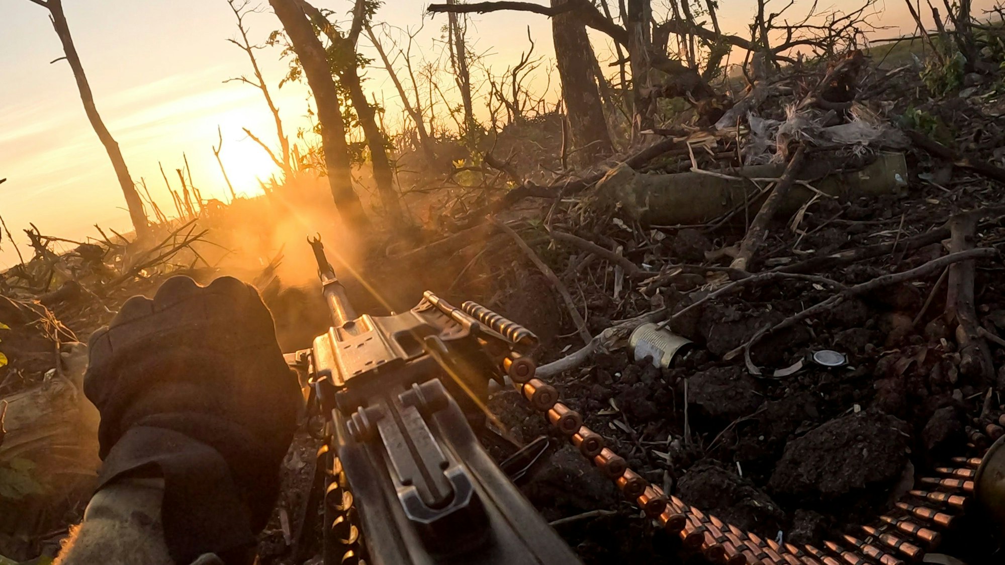 Ein Soldat schaut über sein Maschinengewehr in einen zerstörten Wald.