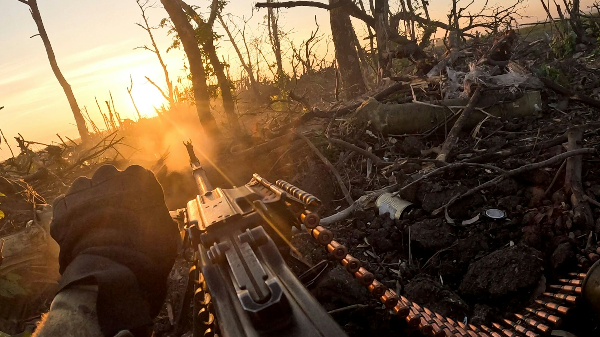 Ein Soldat schaut über sein Maschinengewehr in einen zerstörten Wald.