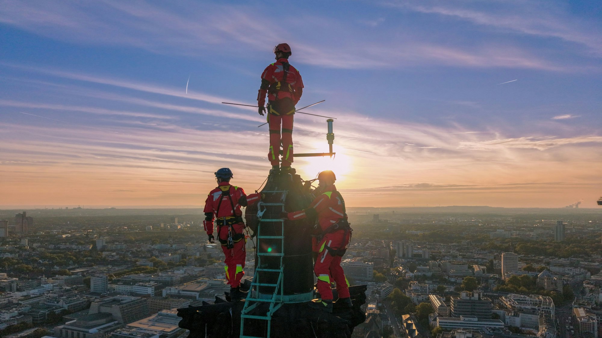 Ein Höhenretter steht am Donnerstag (2.10.2025) auf der Kreuzblume des Kölner Doms in schwindelerregender Höhe.