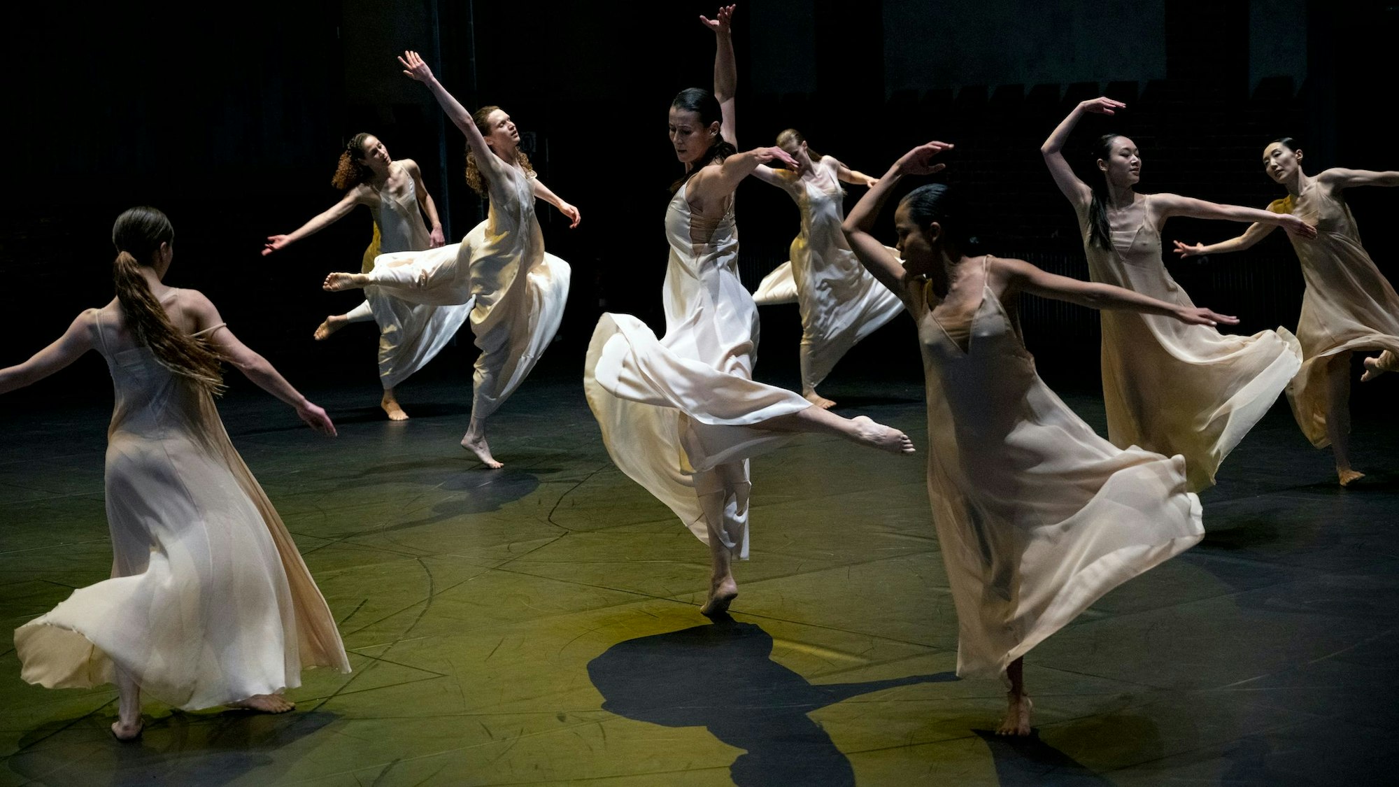 Tänzerinnen in weißen Kleiden springen und hüpfen elegant.